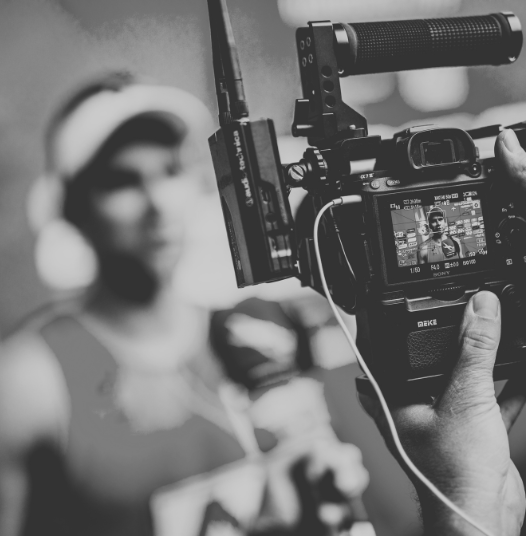 Aufnahme einer Kamera, die eine Frau mit Kopfhörer filmt, im Hintergrund unscharf