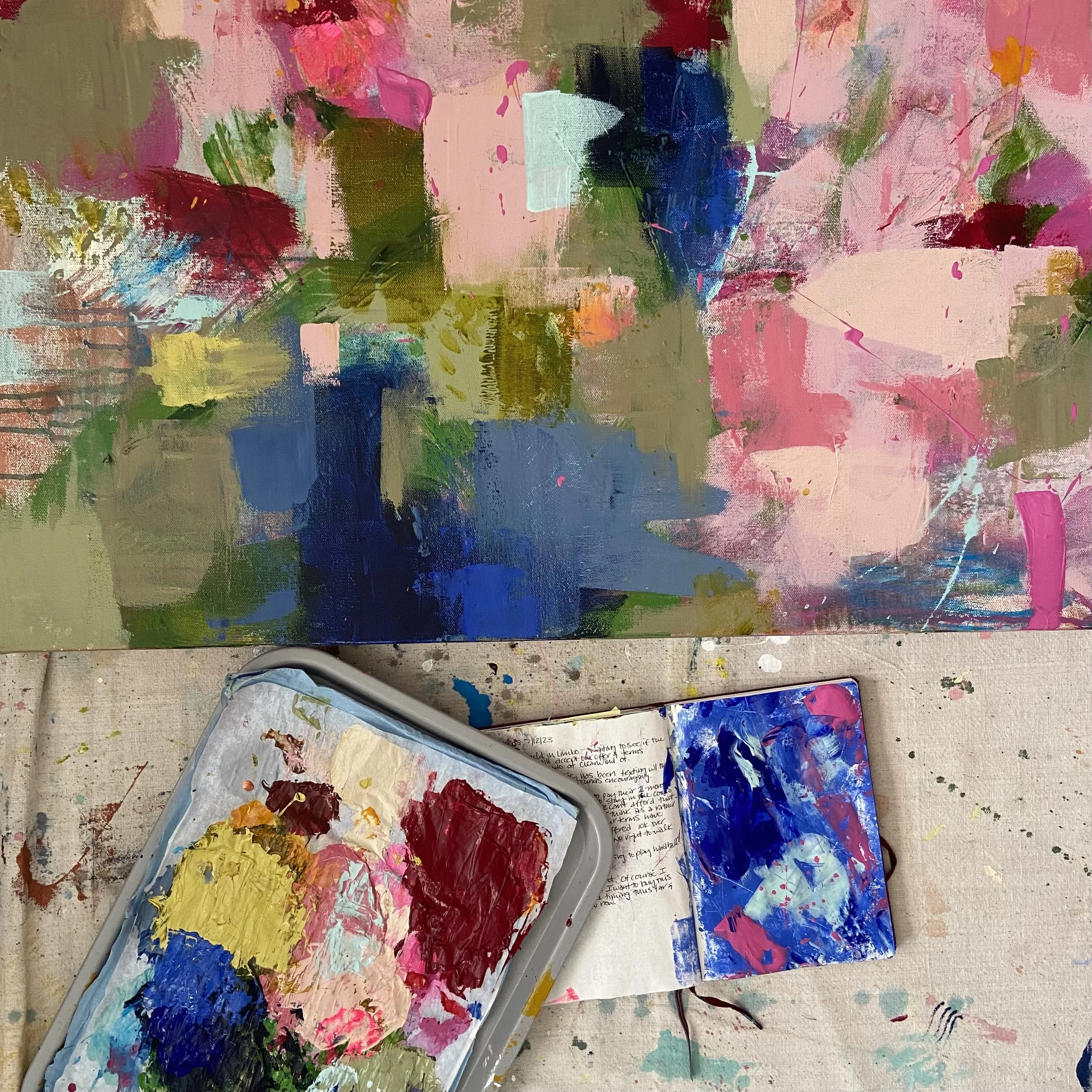 close up view of colorful abstract floral painting and sketchbook