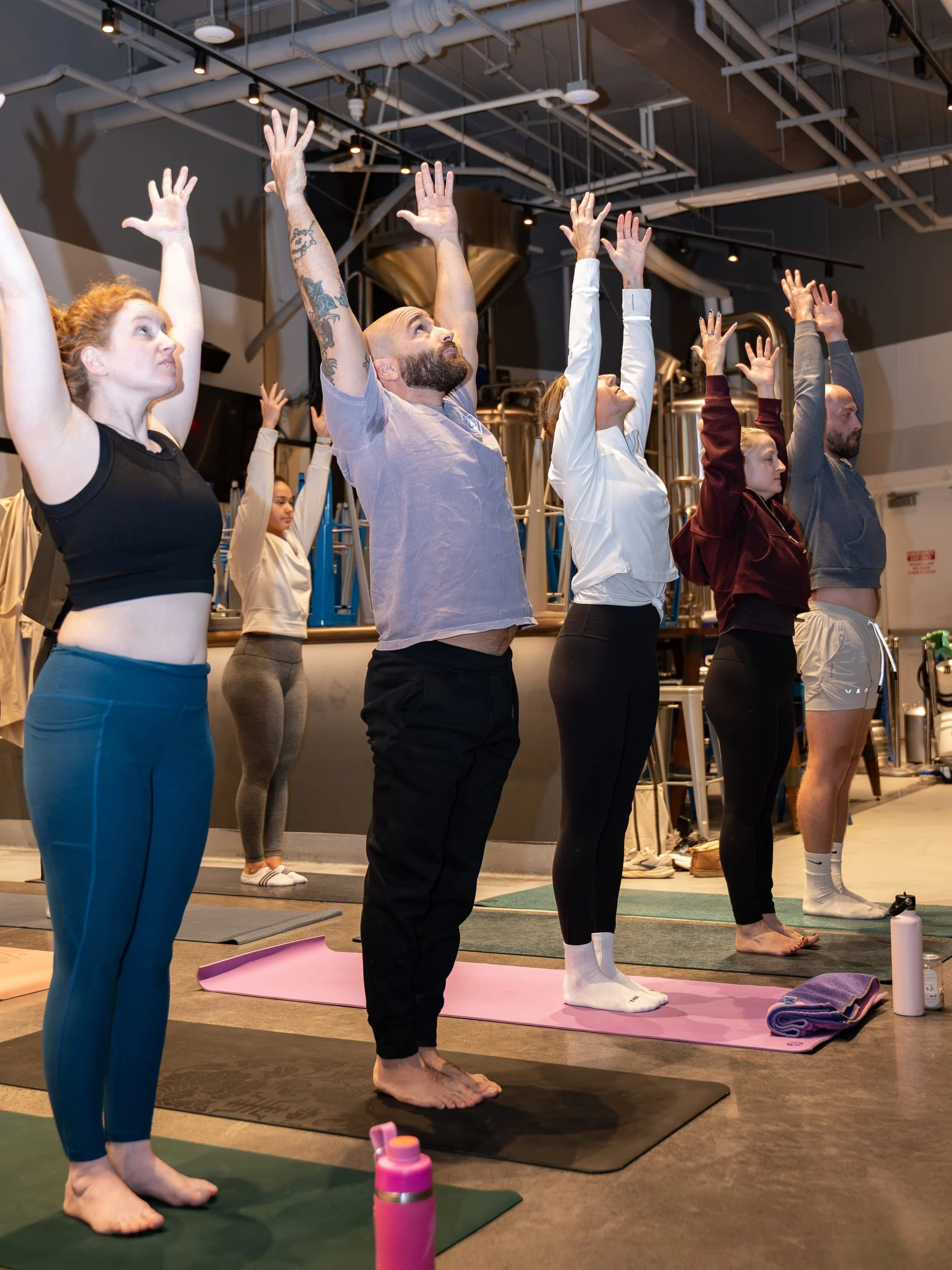 A handful of pop-up event participants with their arms reached into the air practicing a new pilates pose.