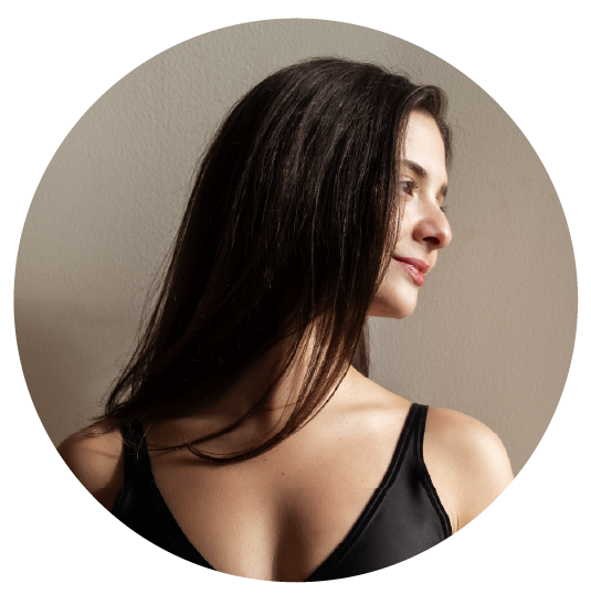 Young woman with long dark hair wearing a black tank top, looking to the side against a neutral background.