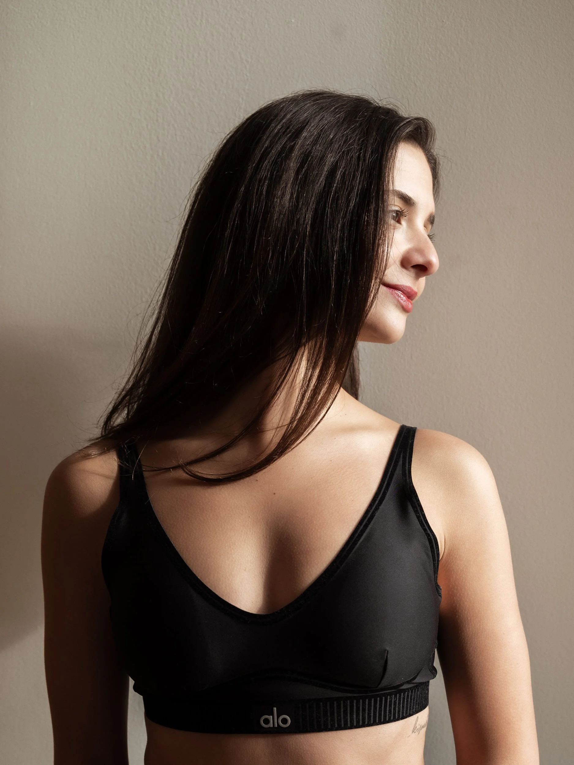 A side profile portrait of Çağla looking to her left side and smiling with natural sun light grazing her face.
