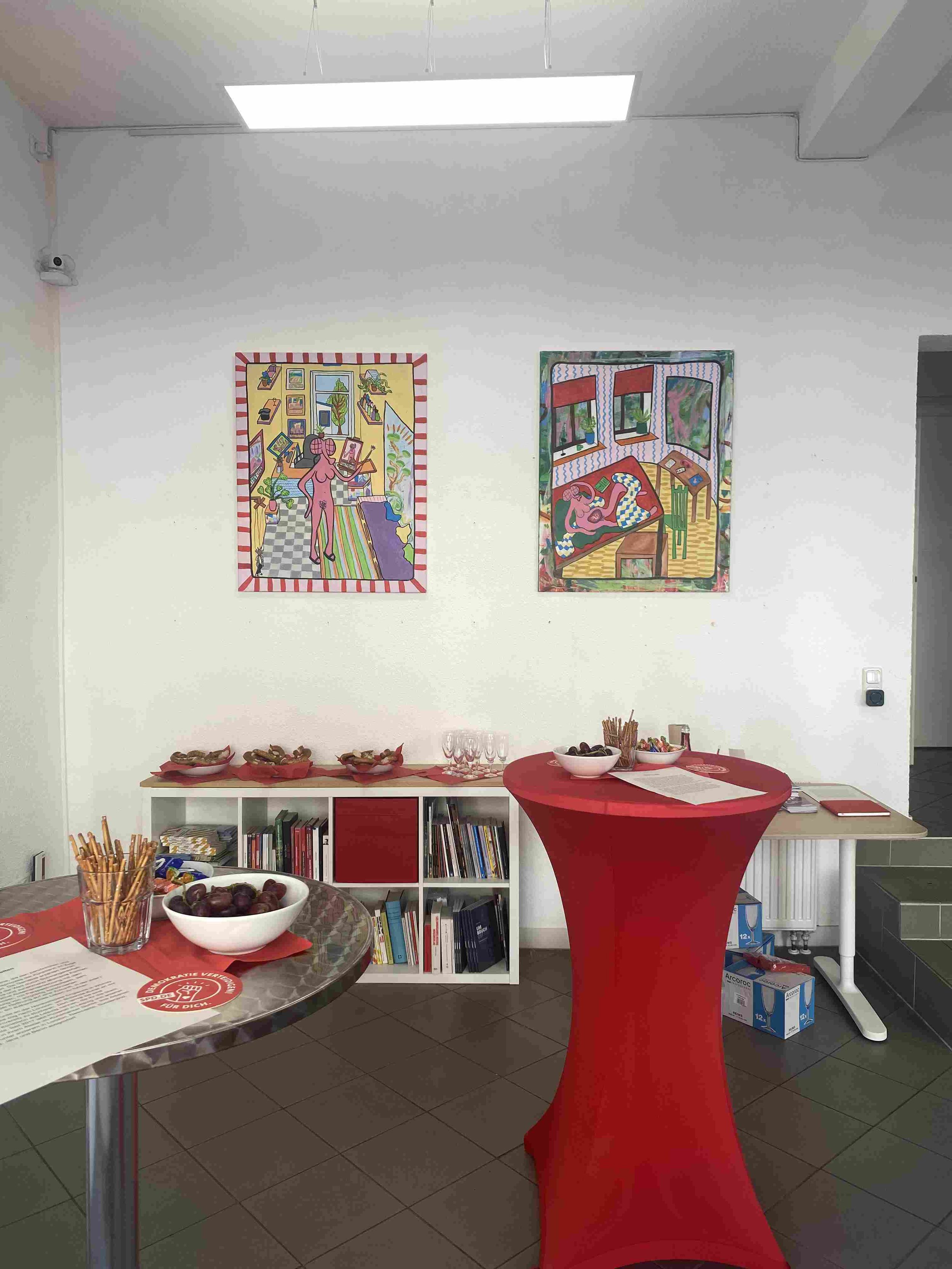 2 paitings in an exhibition with a table in front.jpg