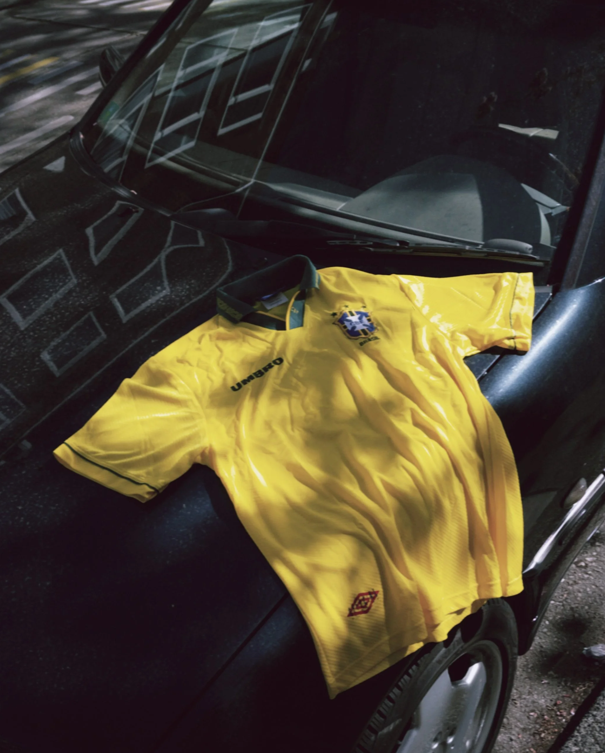 A black car with a yellow sports jacket placed on the car door handle.