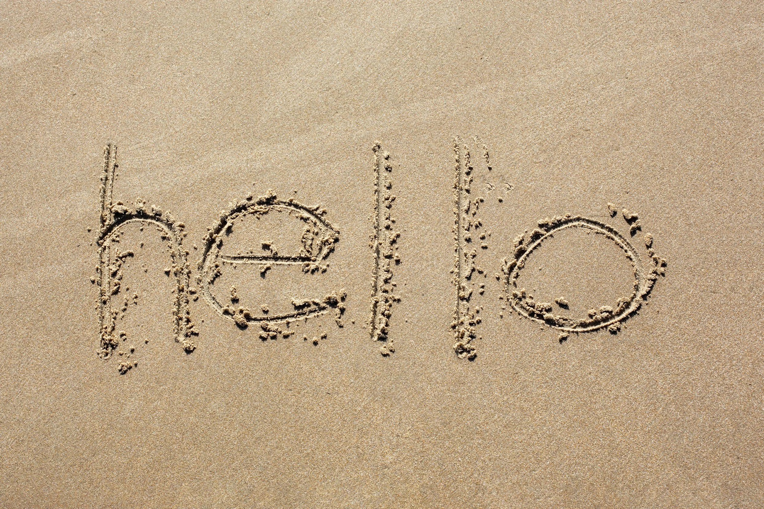 The word 'hello' written in the sand on a beach.