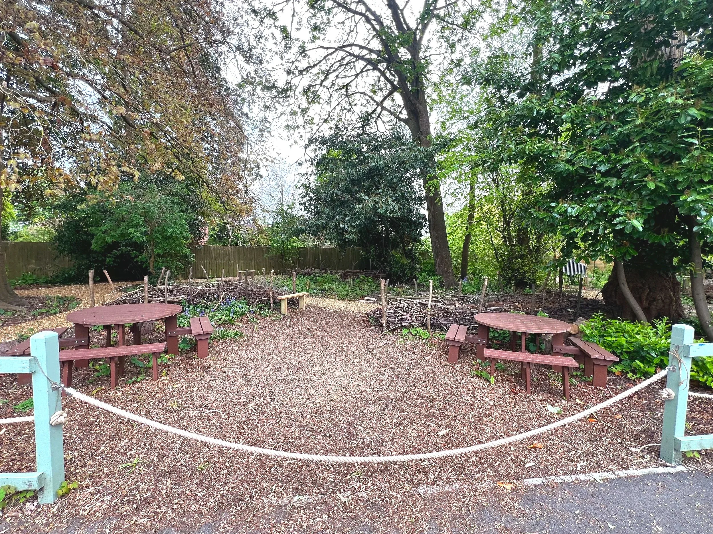 A school's woodland garden, with outdoor seating, dead hedges, trees and naturalistic planting