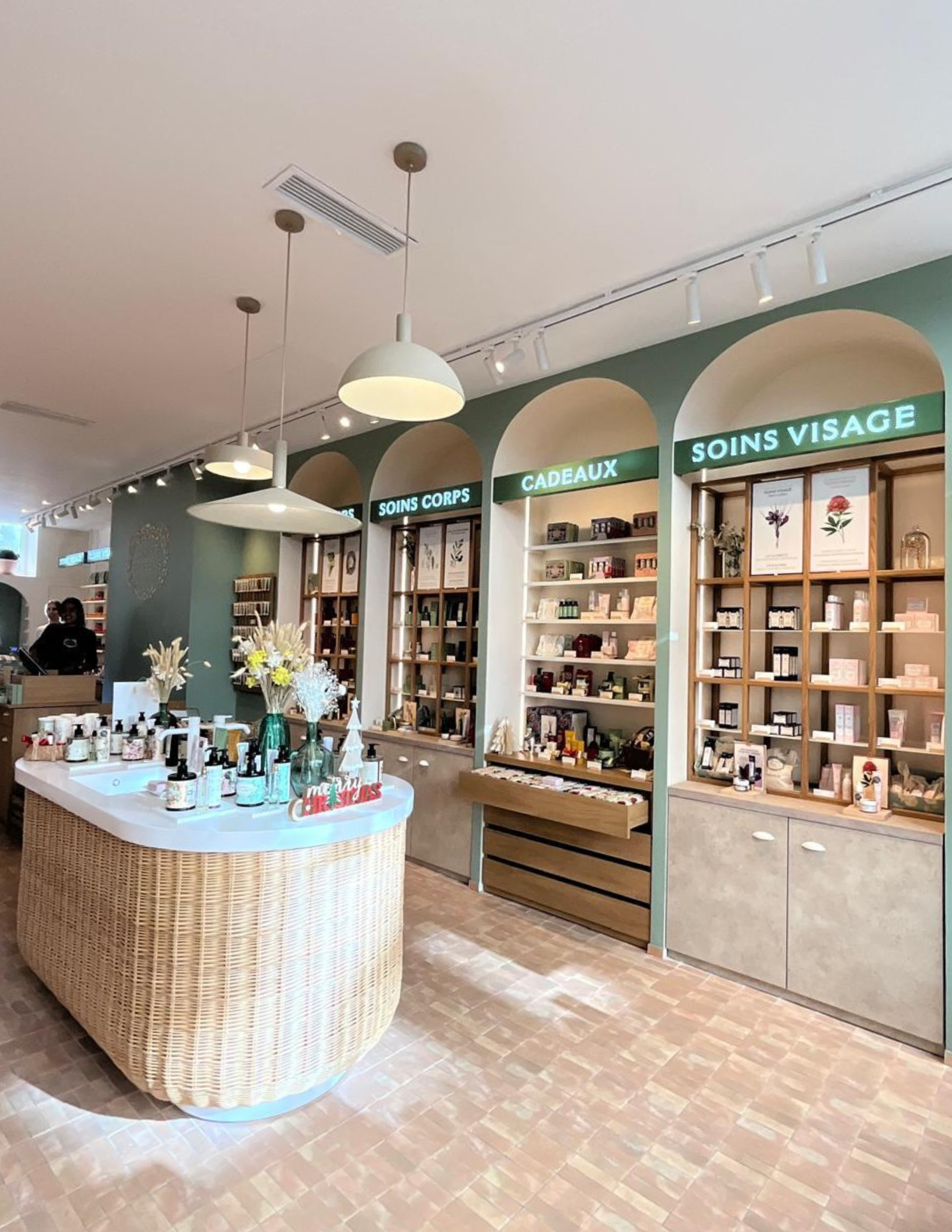 Vue intérieure d’un magasin de produits de soin et de beauté, avec des étagères étiquetées « SOINS CORPS », « CADEAUX » et « SOINS VISAGE »