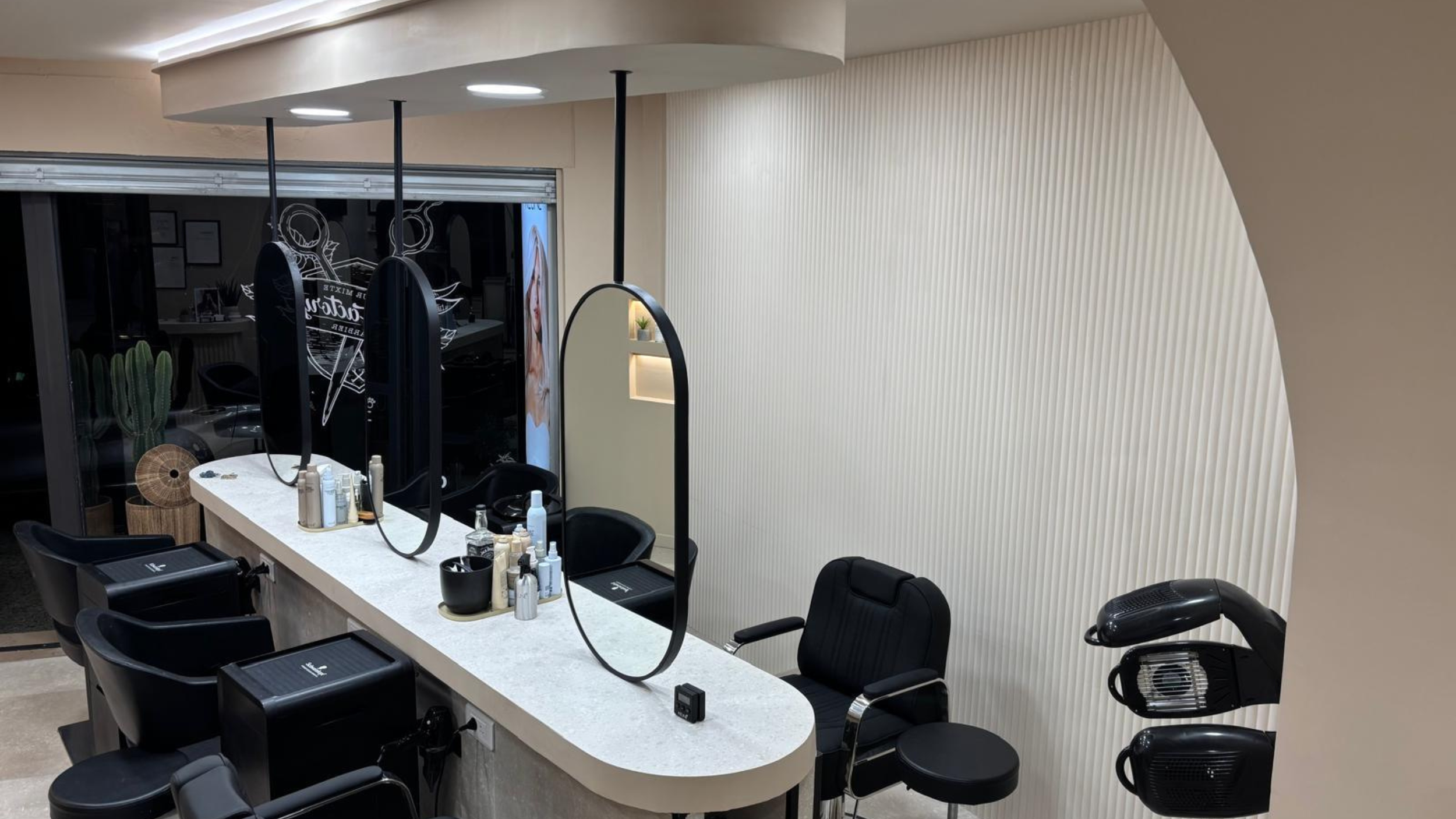 Poste de salon de coiffure moderne avec des fauteuils noirs, des outils de coiffage et des miroirs dans un intérieur contemporain.