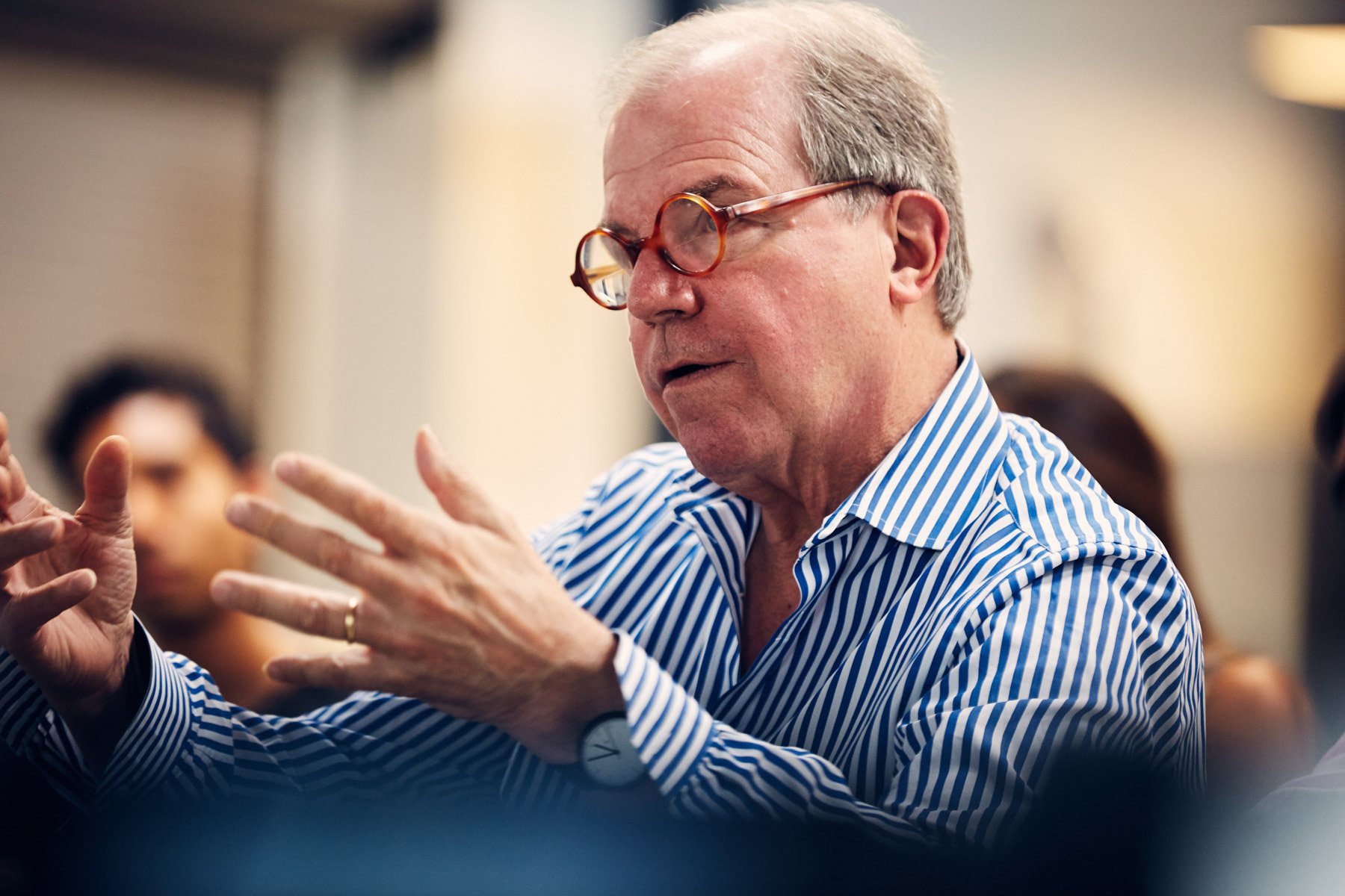 A person wearing glasses and a blue striped shirt gestures while speaking in a meeting or discussion setting for Piaggio Fast Forward in Boston Massachusetts
