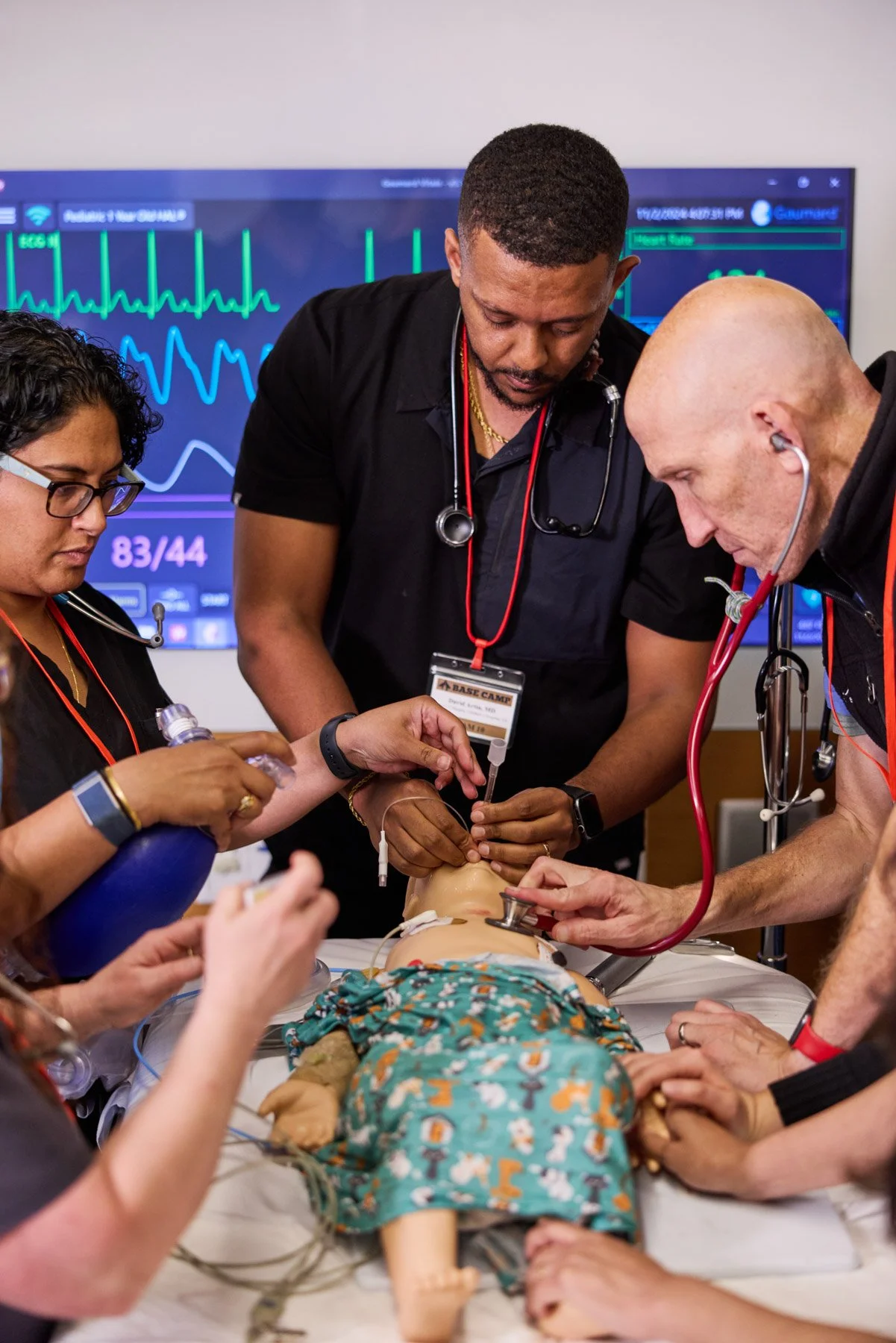 Medical team practices on a pediatric mannequin with monitoring screen in the background at Cornell PEM Base Camp