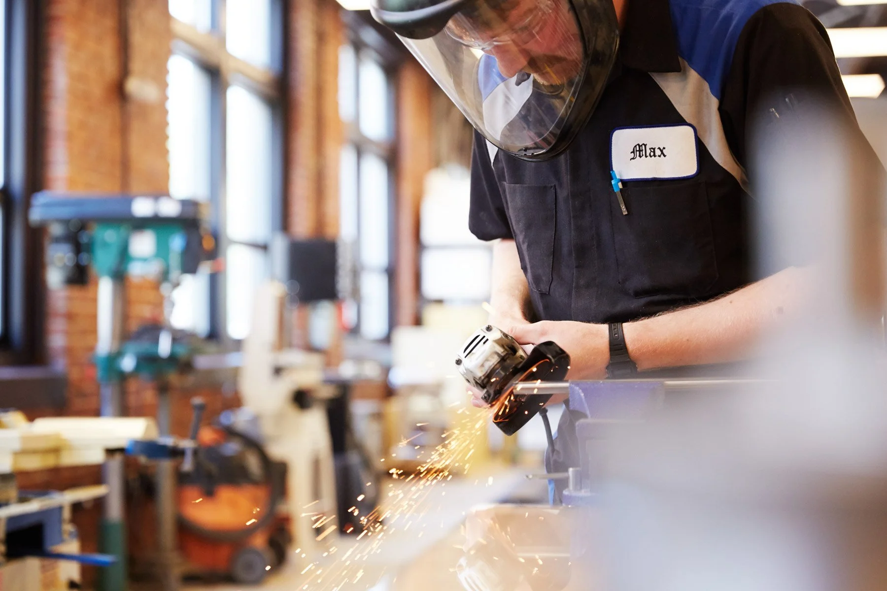 Worker using a power tool in a workshop, wearing protective gear at Piaggio Fast Forward in Boston Massachusetts