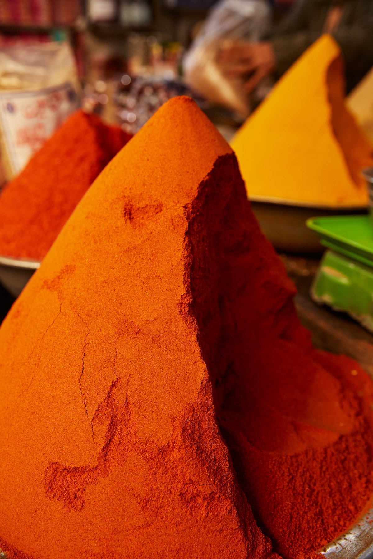 Close-up of colorful spice blends, including bright orange and red, arranged in pyramid shapes. Empress Market Karachi Pakistan