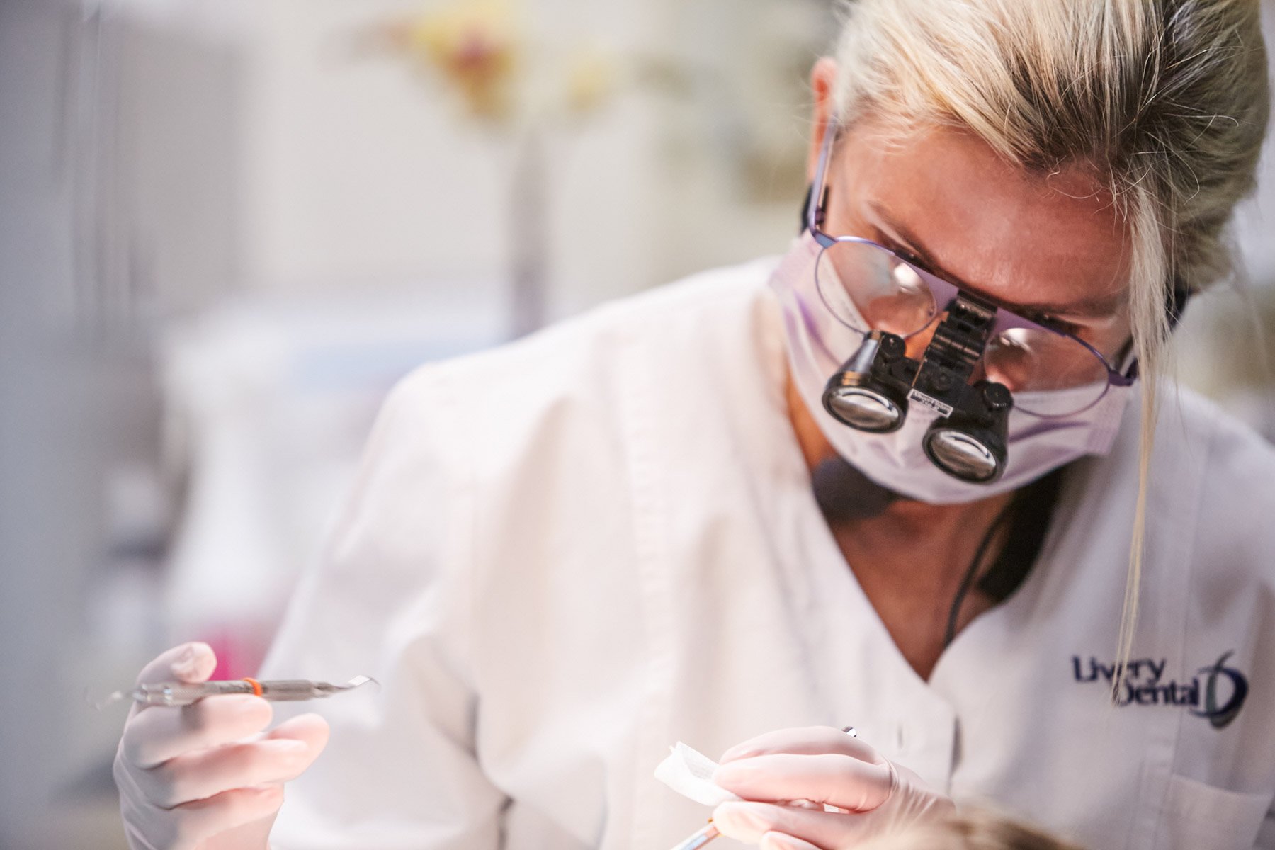 A female scientist wearing protective goggles and a face mask working with a pipette and small container in a laboratory.