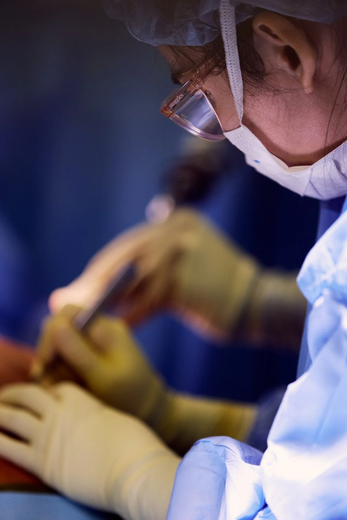 A person wearing safety glasses, a surgical mask, and gloves, working in a laboratory or medical setting, using a pen or stylus. At Mount Sinai Hospital in New York City