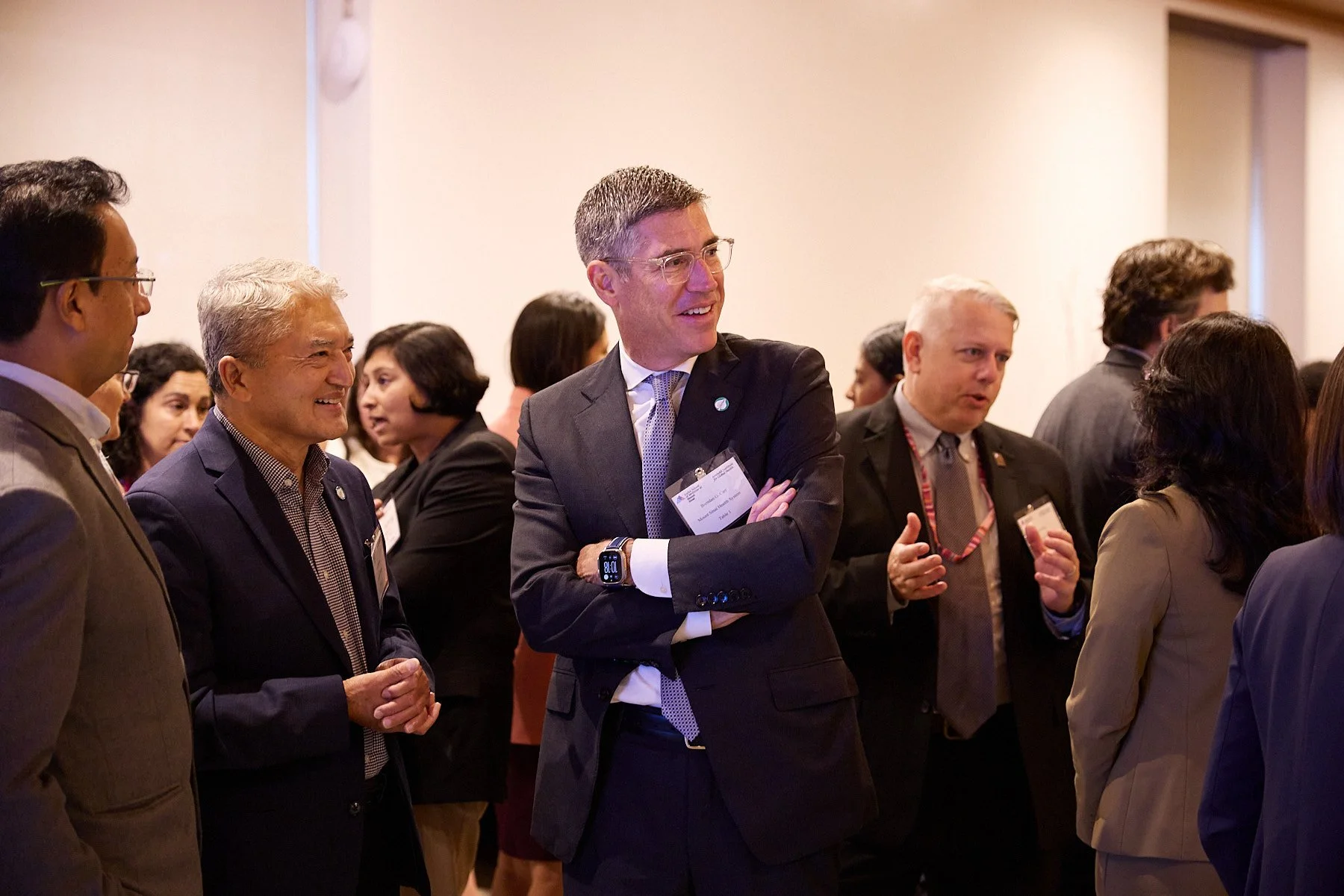 Group of professional men and women engaging in conversation at a conference or business event.