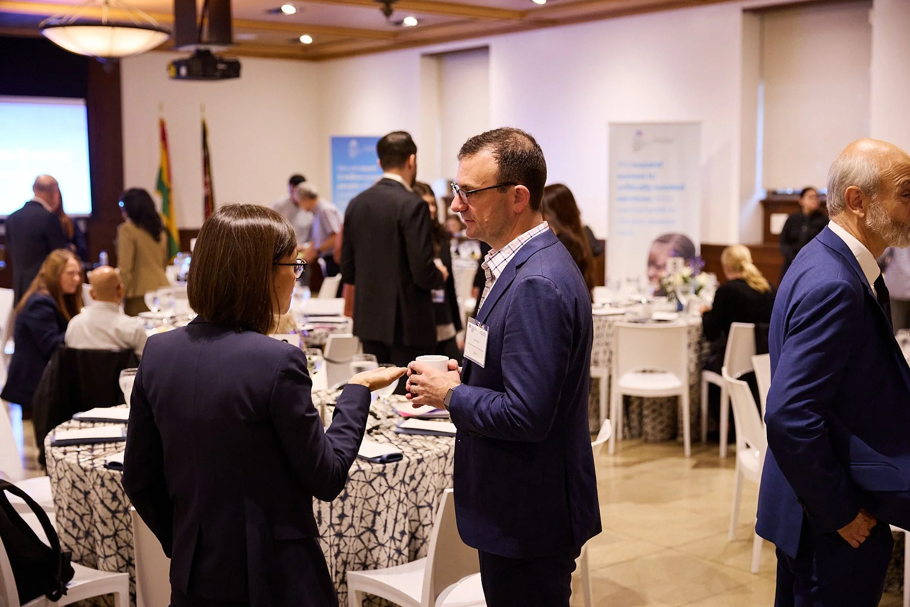 People networking and conversing at a conference or professional event in a banquet hall.