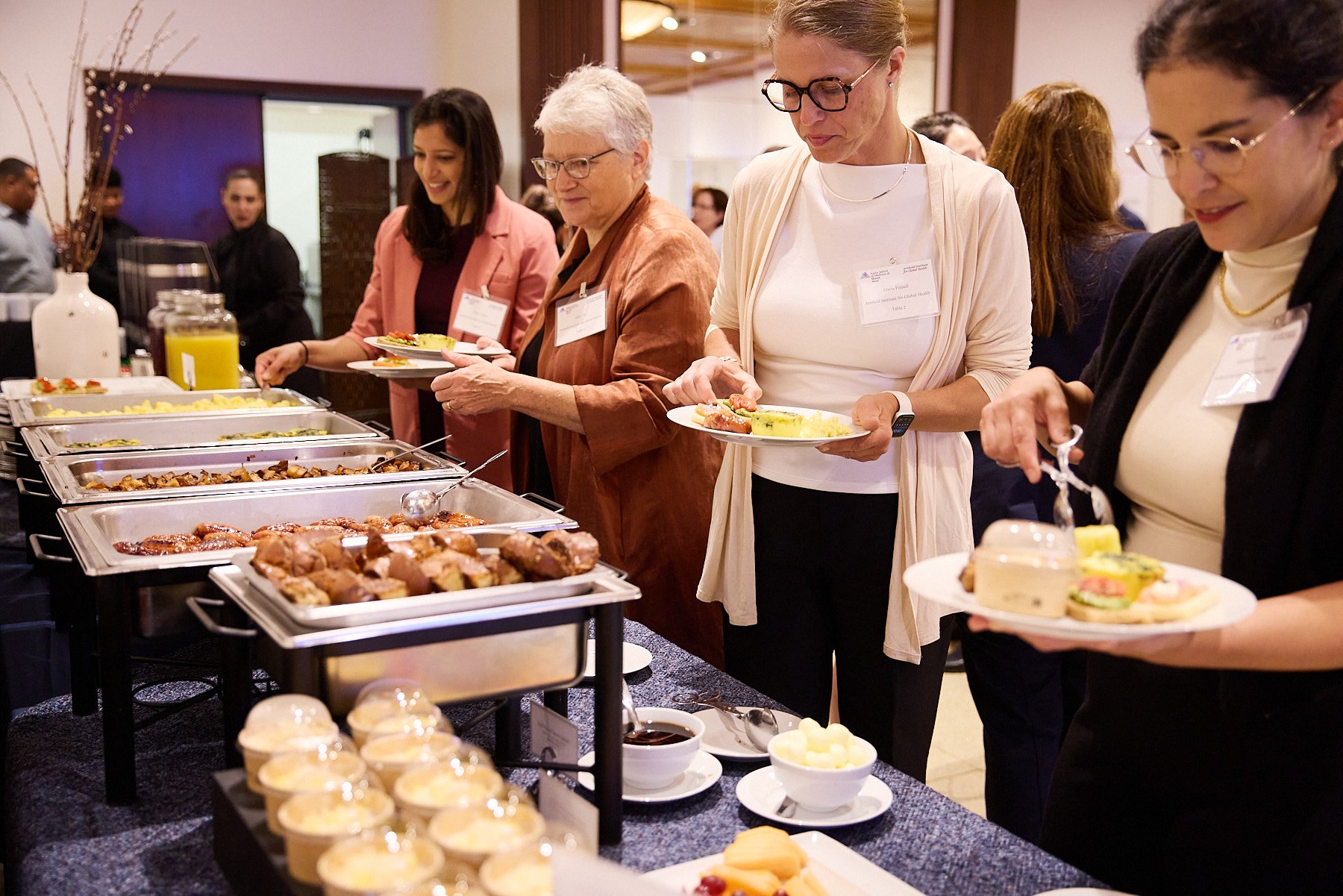People serving themselves food from a buffet table at a conference or event.