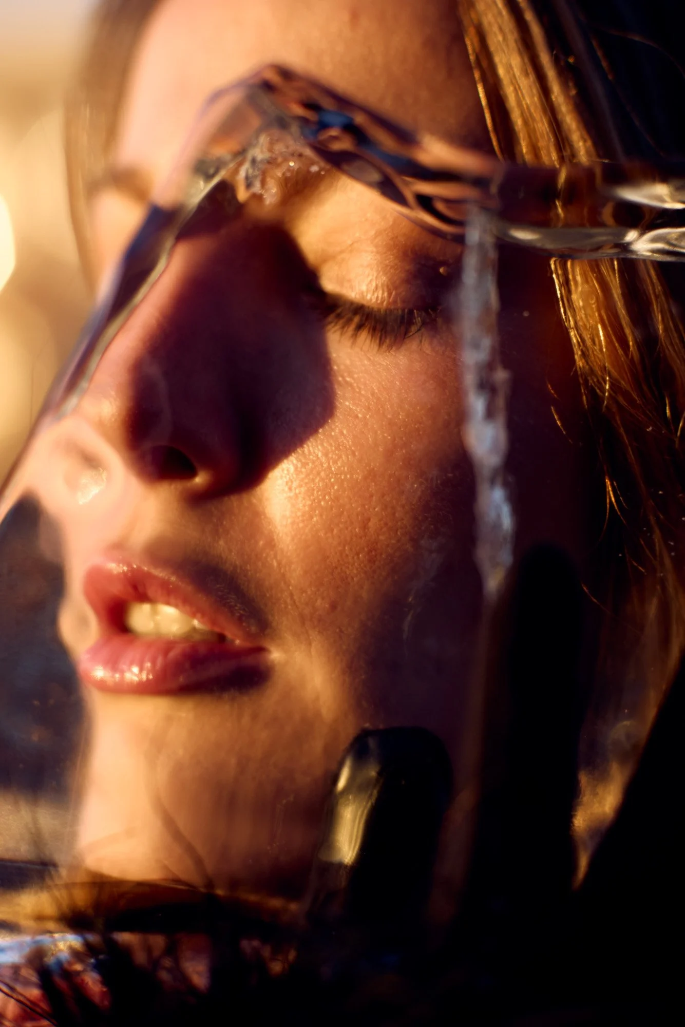 Close-up of Taylore Crosley with closed eyes, partially obfuscated through a large piece of ice.