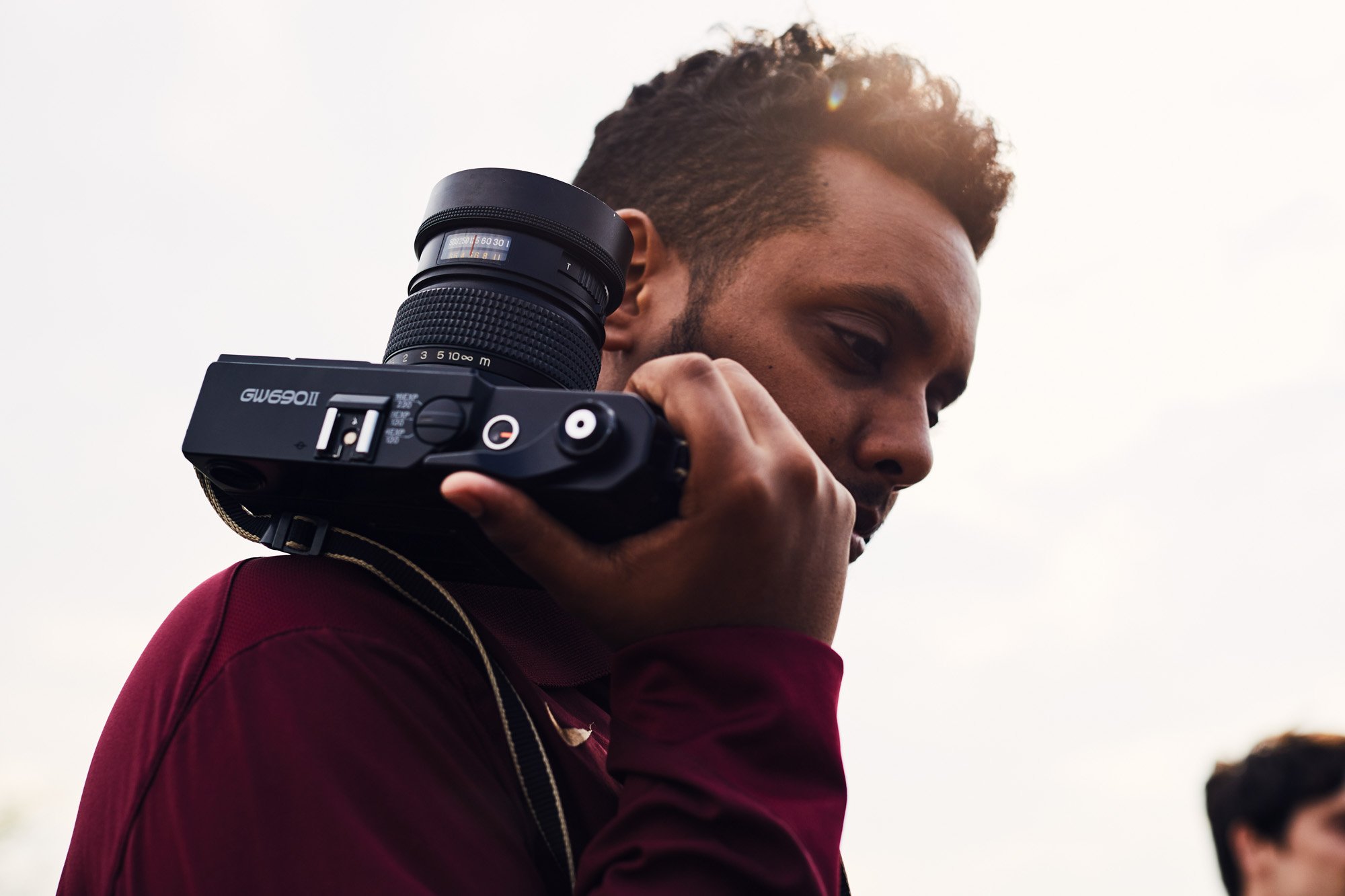 Photographer Mehron Menghistab a camera over his shoulder while outdoors.