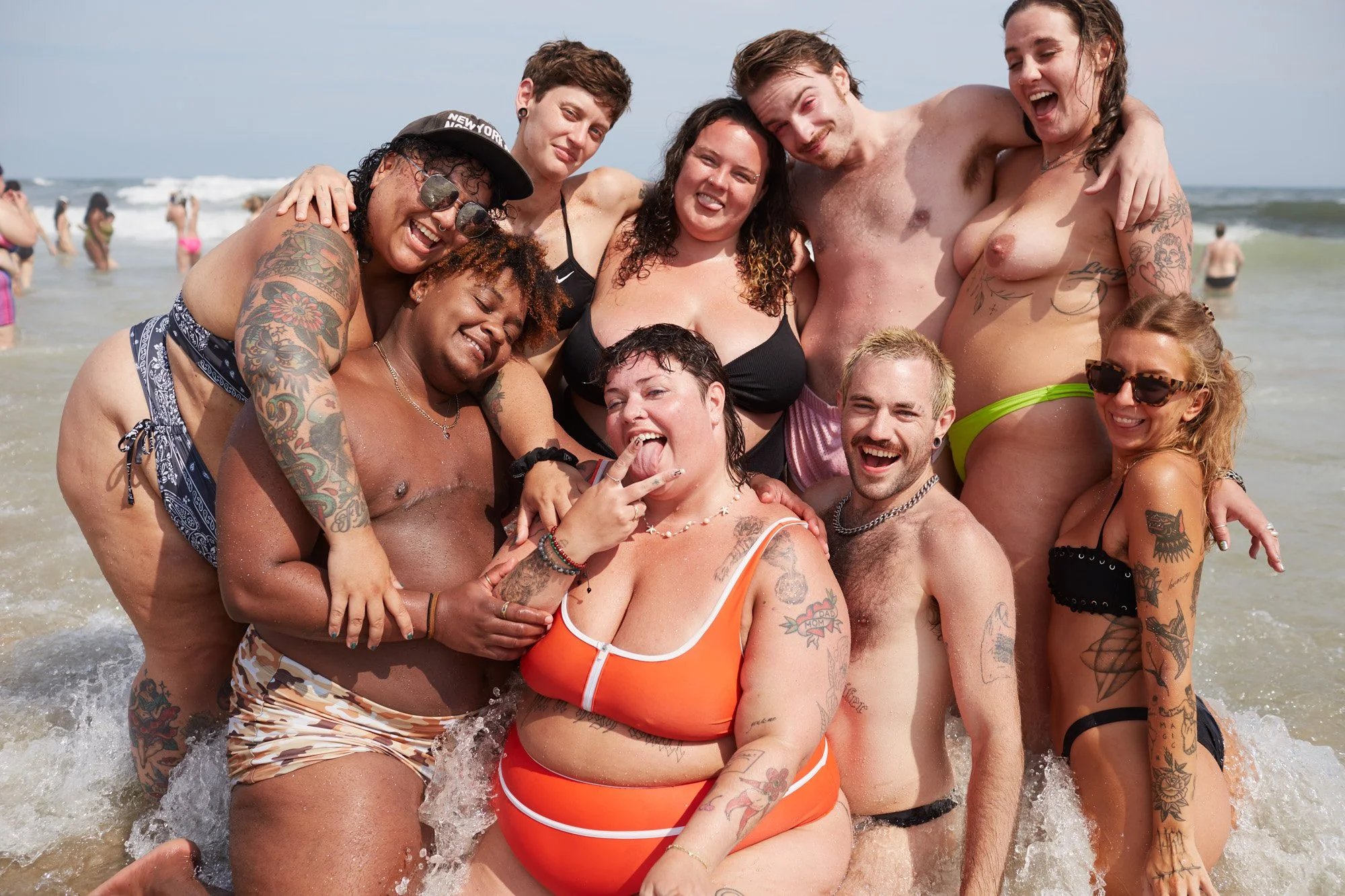 Group of friends enjoying at the beach, smiling and posing for a photo in the water. Pride Jacob Riis Beach New York City