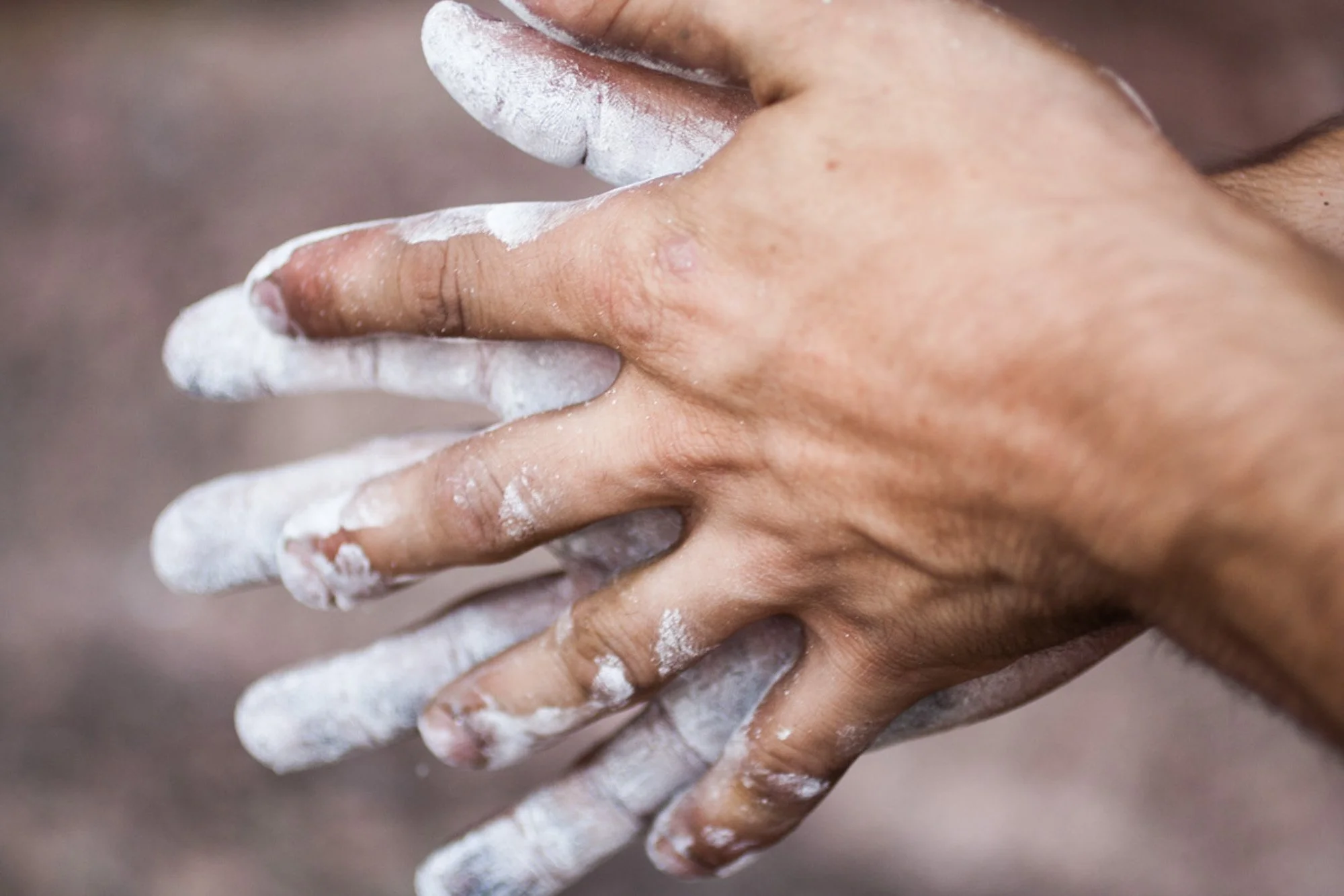Close-up of a hand covered in white powder, with some powder on lips and face.