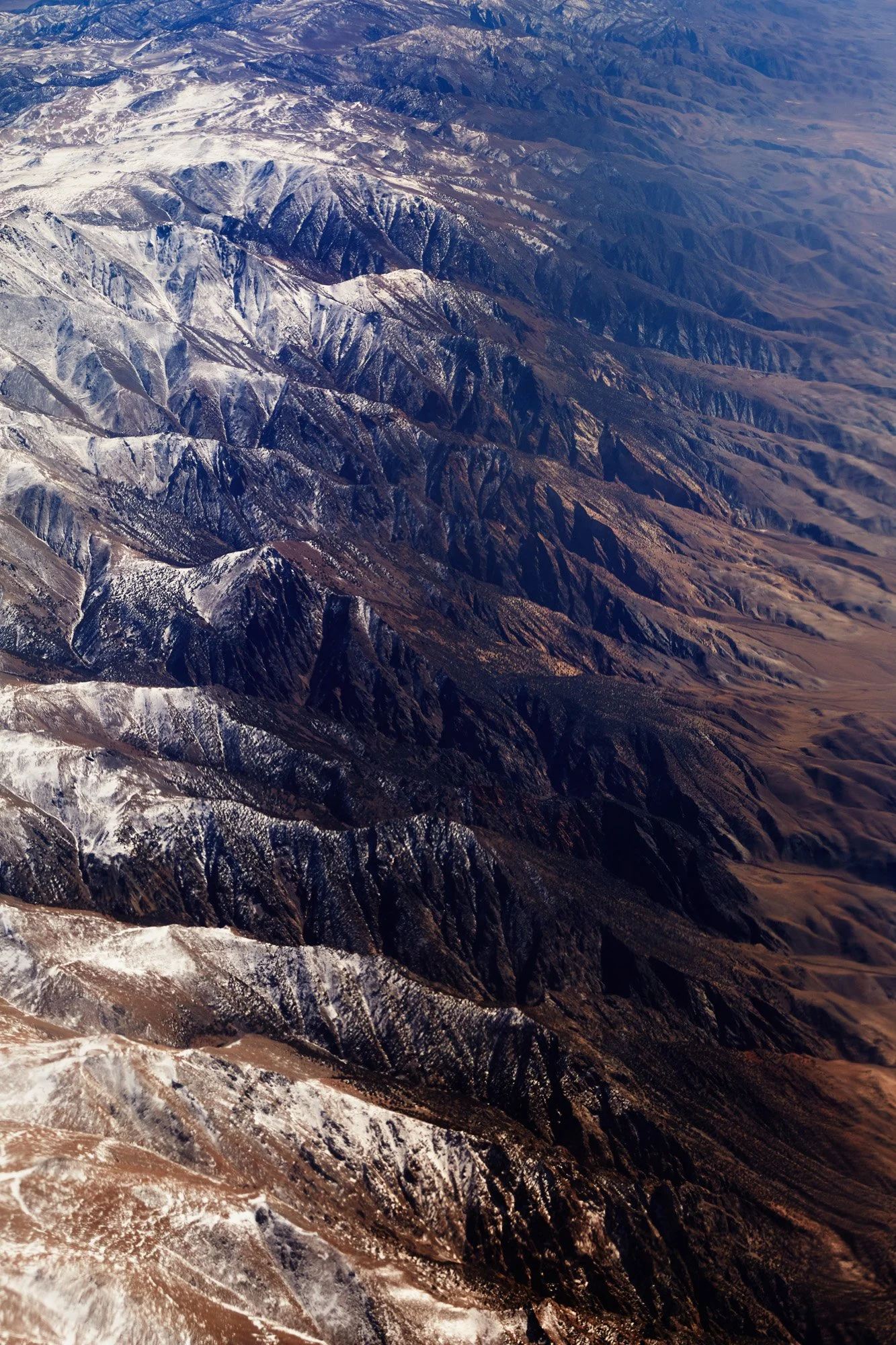 Aerial view of snow-capped mountain range with rugged peaks and valleys in Nevada.