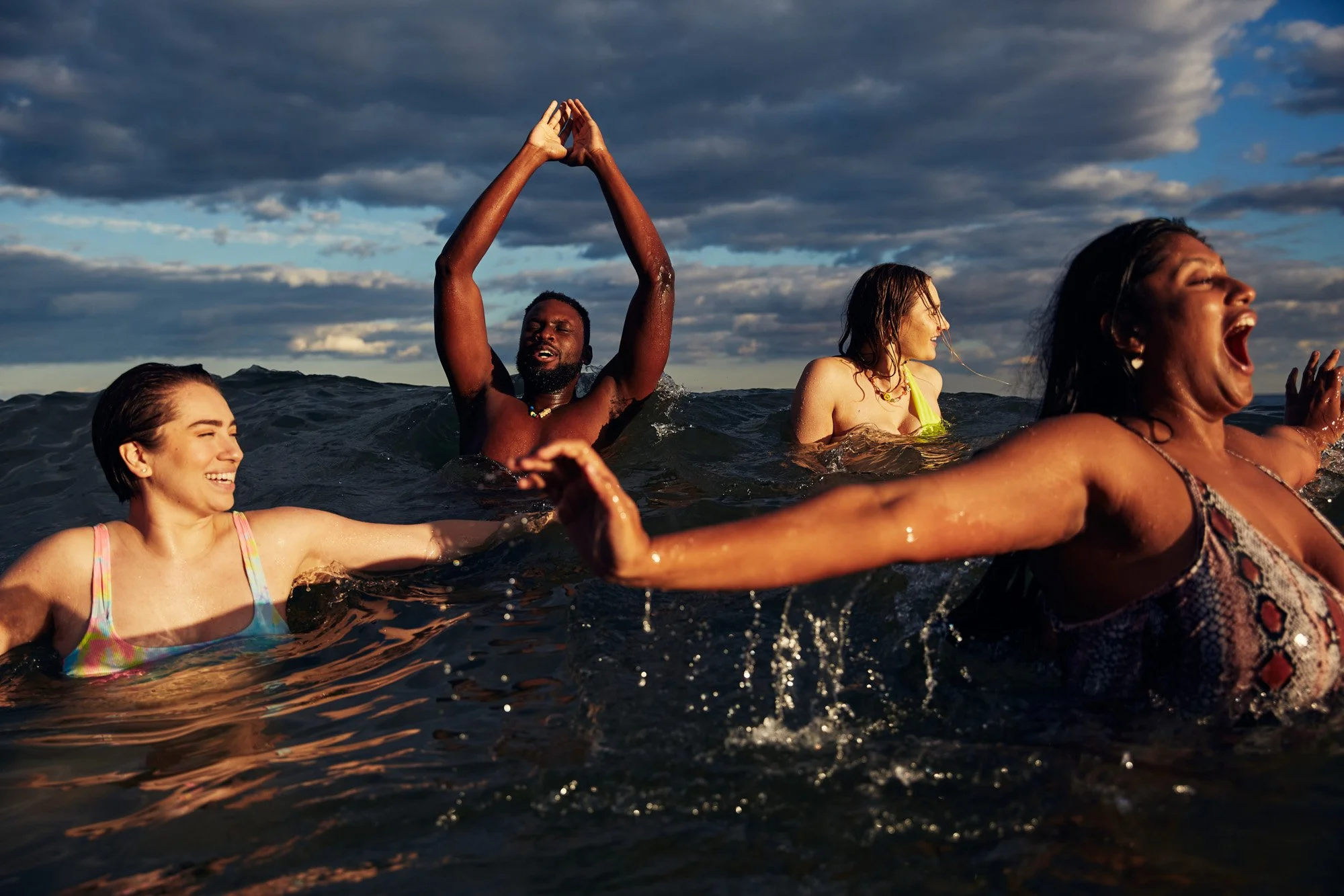 People swimming and having fun in the ocean during sunset with a cloudy sky, Rockaway Beach Queens New York City