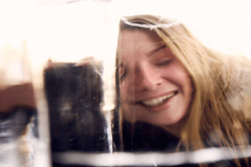 Taylore Crosley looking through a large piece of ice, warping her face and making her laugh.