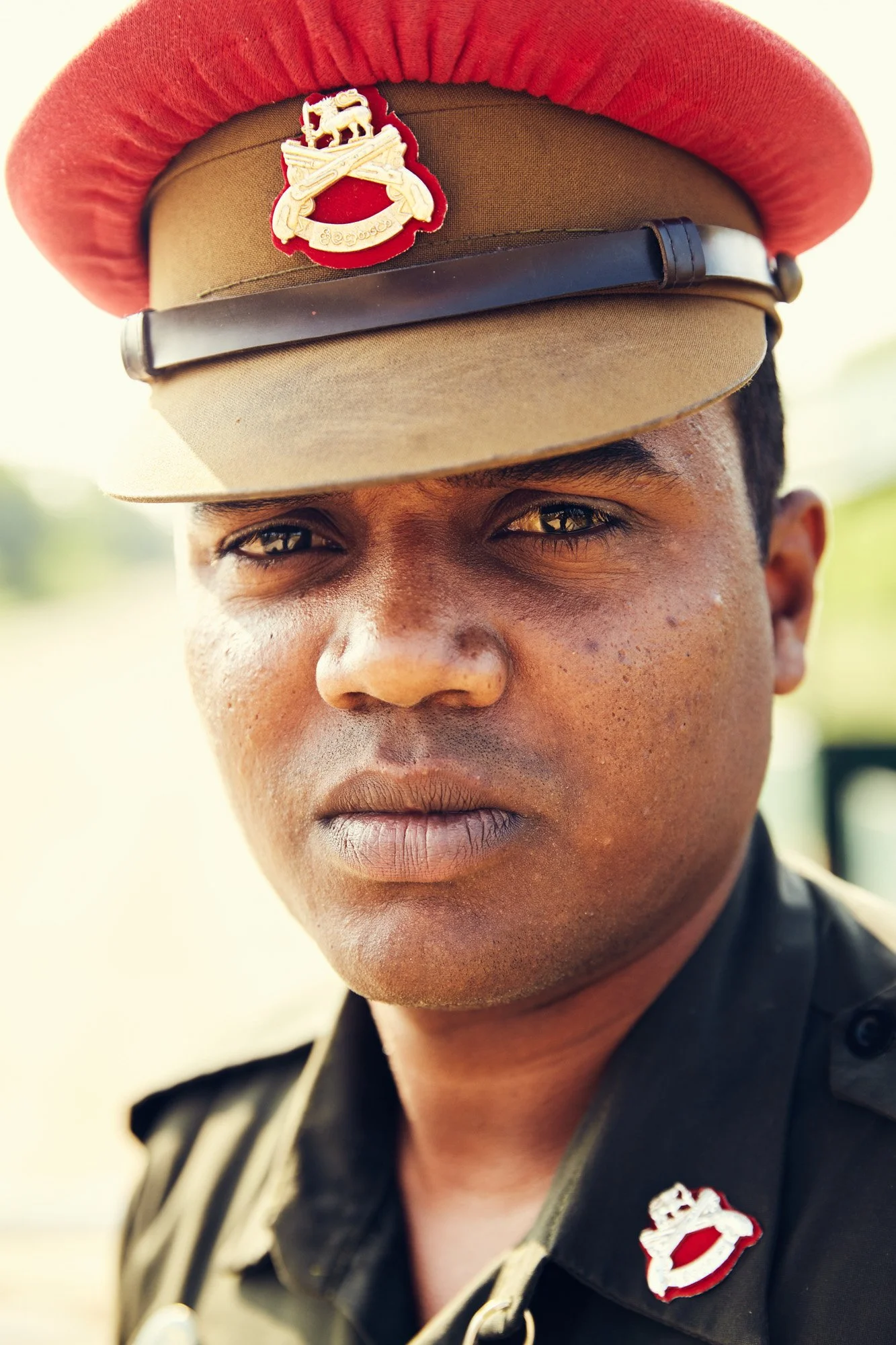 Close-up of a young male police officer wearing a khaki uniform and a cap with a badge, outdoors on a sunny day. Jaffna Sri Lanka