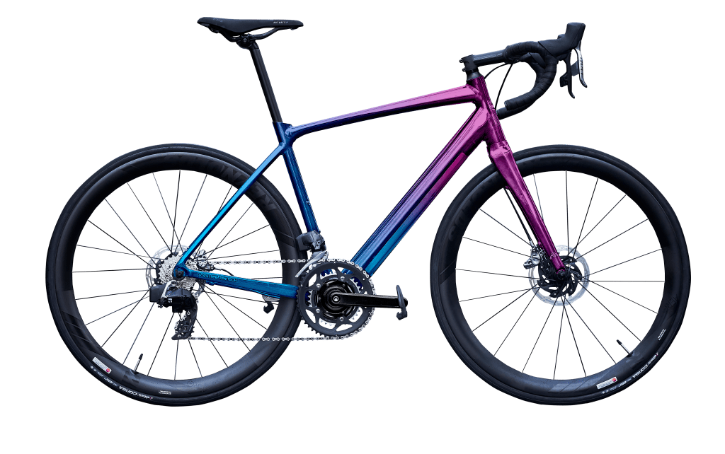 A colorful modern mountain bike with a pink and purple gradient frame, black tires, and gear components.