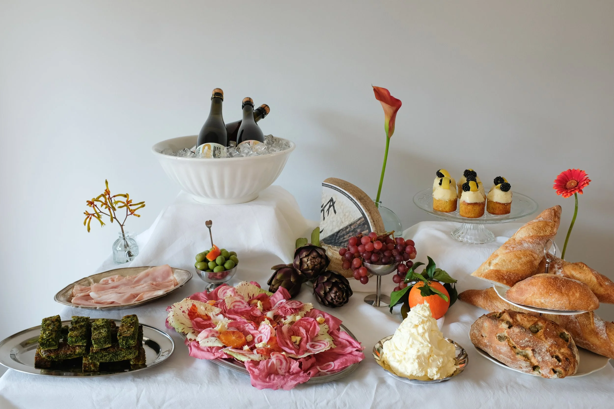 Elegant and stylish grazing table with cheeses, wines, whipped butter, salad, olives and cupcakes in Zurich, Switzerland by Larissa Sterchi.