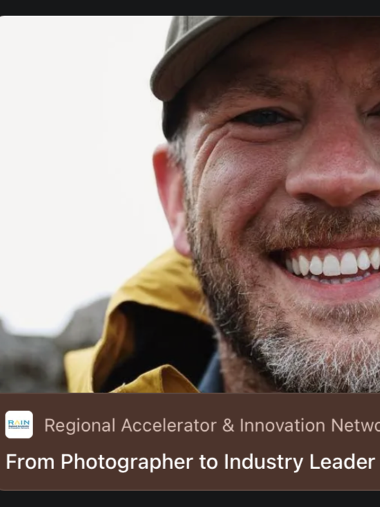 Close-up of a smiling man wearing a gray cap and yellow jacket