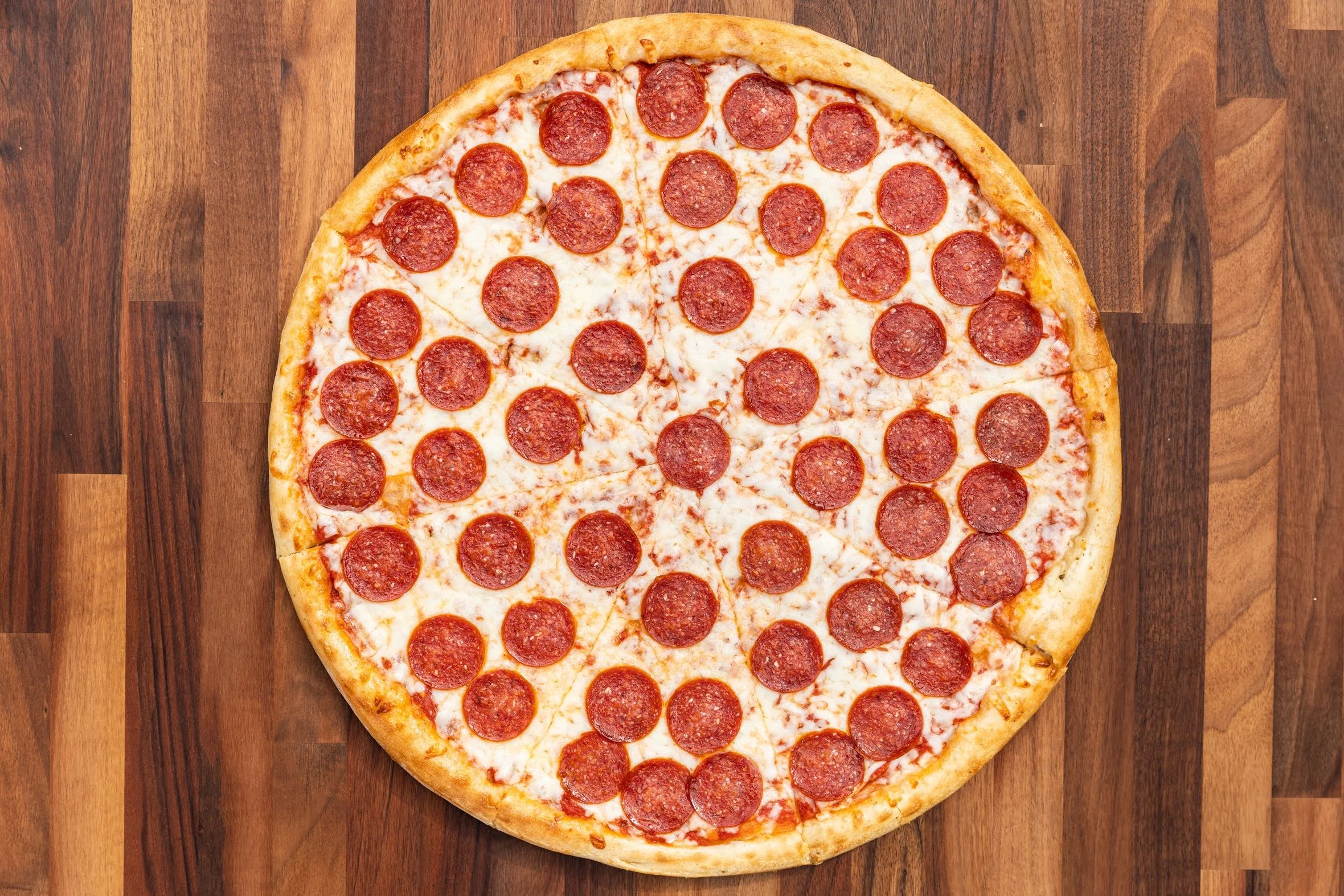 A pepperoni pizza with cheese on a wooden table.