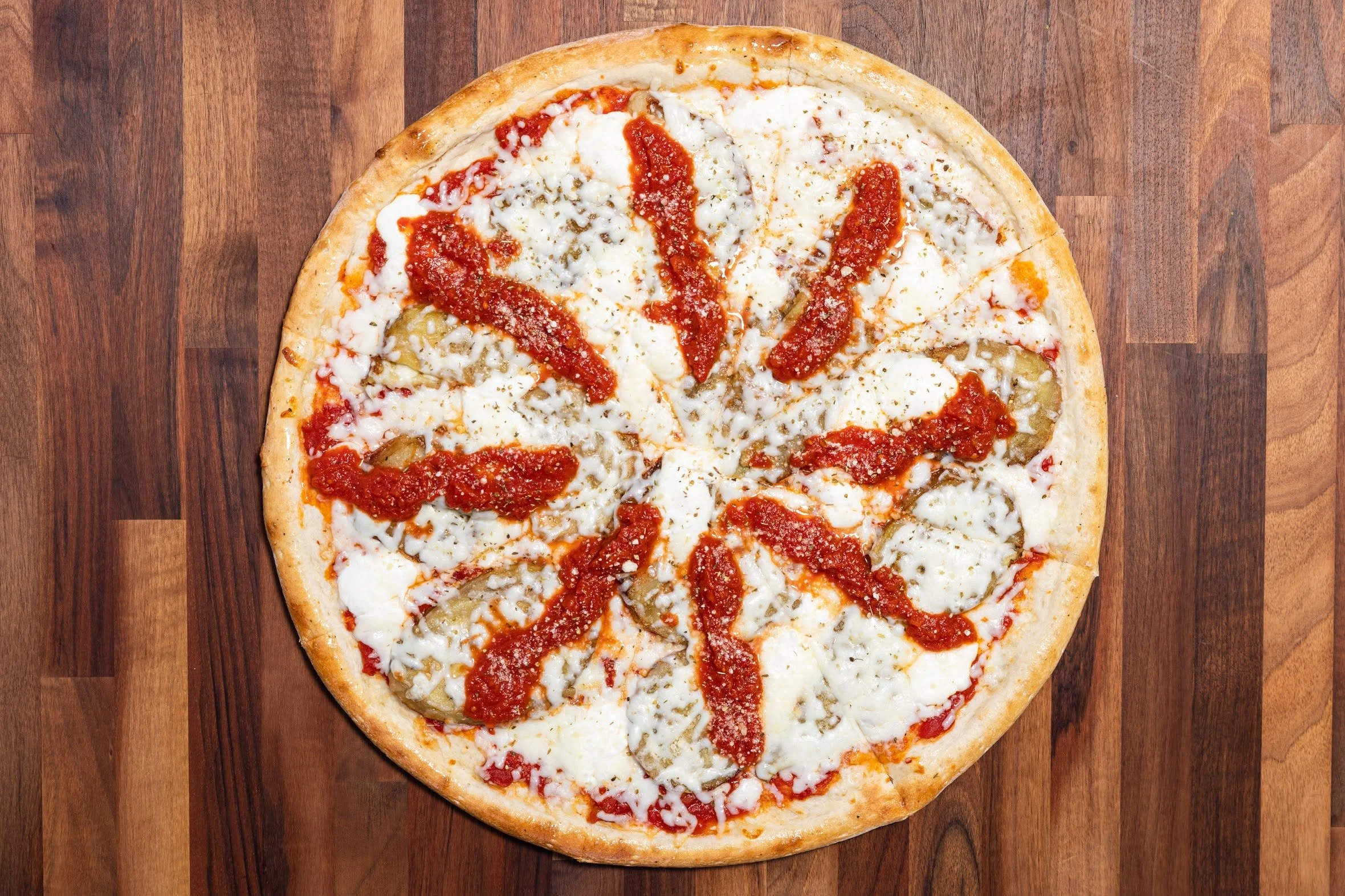 A pizza with mozzarella cheese, tomato sauce, and pepperoni slices on a wooden surface.