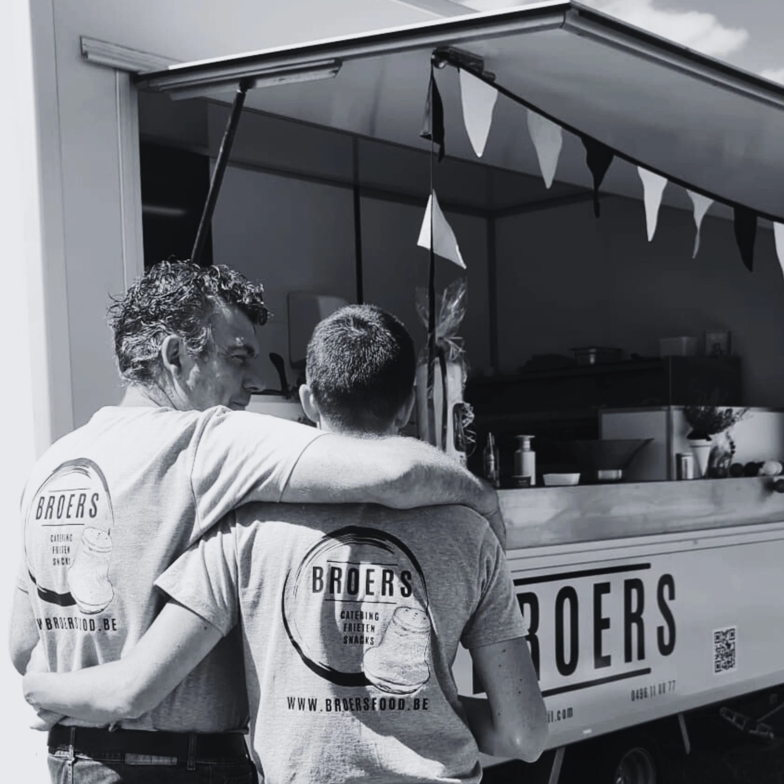 Twee mannen met shirt met logo Brothers Food staan voor een foodtruck, met de arm van de ene man om de schouder van de andere. De foodtruck heeft banner en QR-code.
