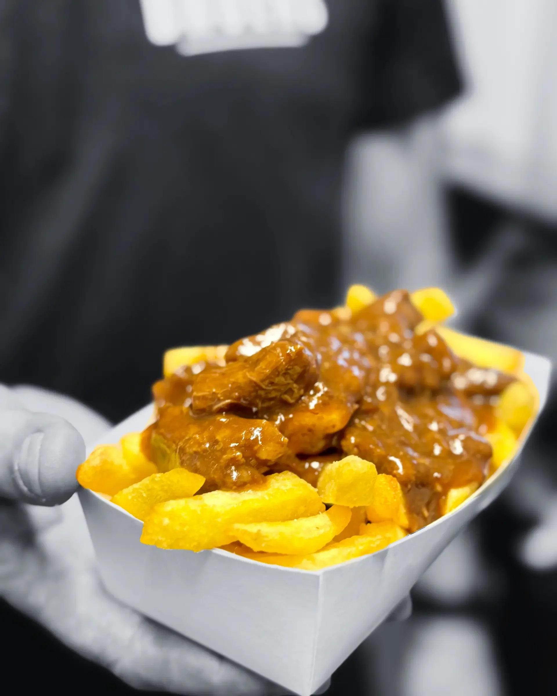 Portie frieten met gehakt en saus, in een kartonnen bakje