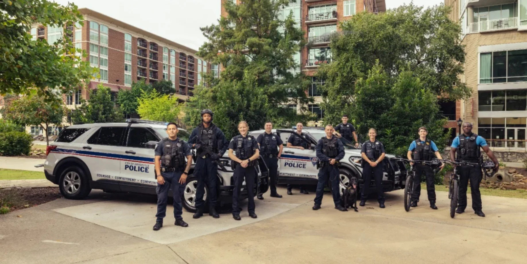 Greenville Police Department officers standing with patrol vehicles, bicycles, and a K9 in downtown Greenville