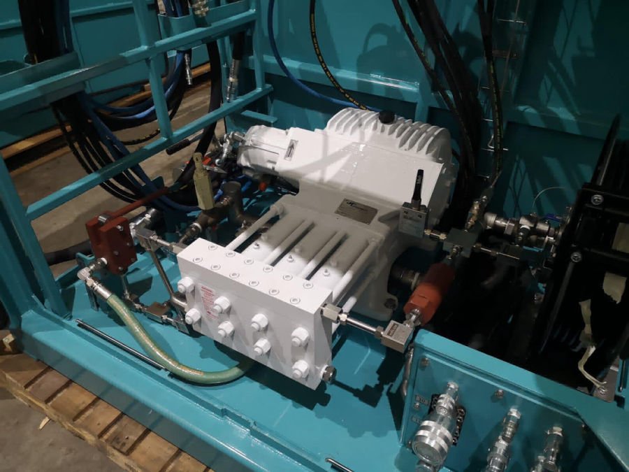Close-up of industrial machinery with hydraulic valves, pipes, and controllers on a blue metal frame.