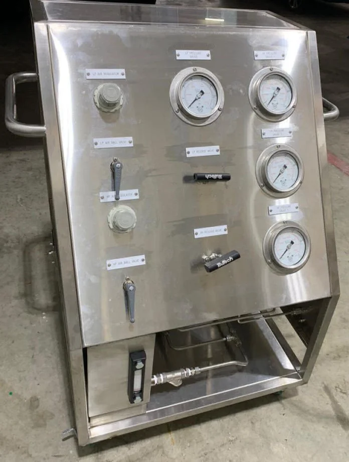Stainless steel industrial control panel with four pressure gauges, two valves, and labels indicating various gas and air connections, situated on a concrete floor.