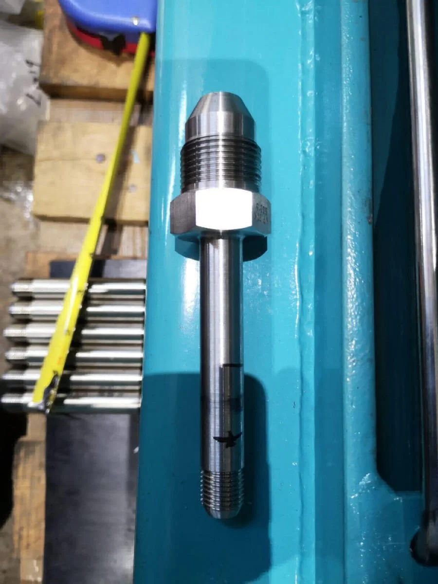 A close-up of a metallic bolt with a hexagonal nut, placed on a blue engineered surface.