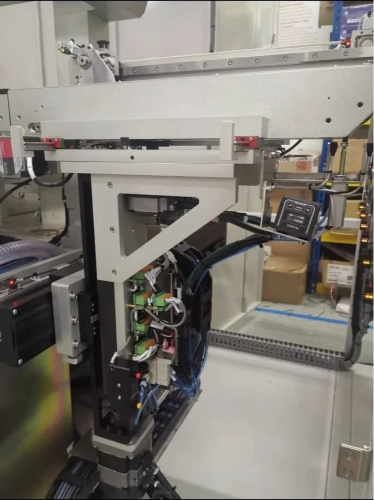 Close-up of a complex industrial robotic arm with wiring and components, situated in a manufacturing or lab setting.