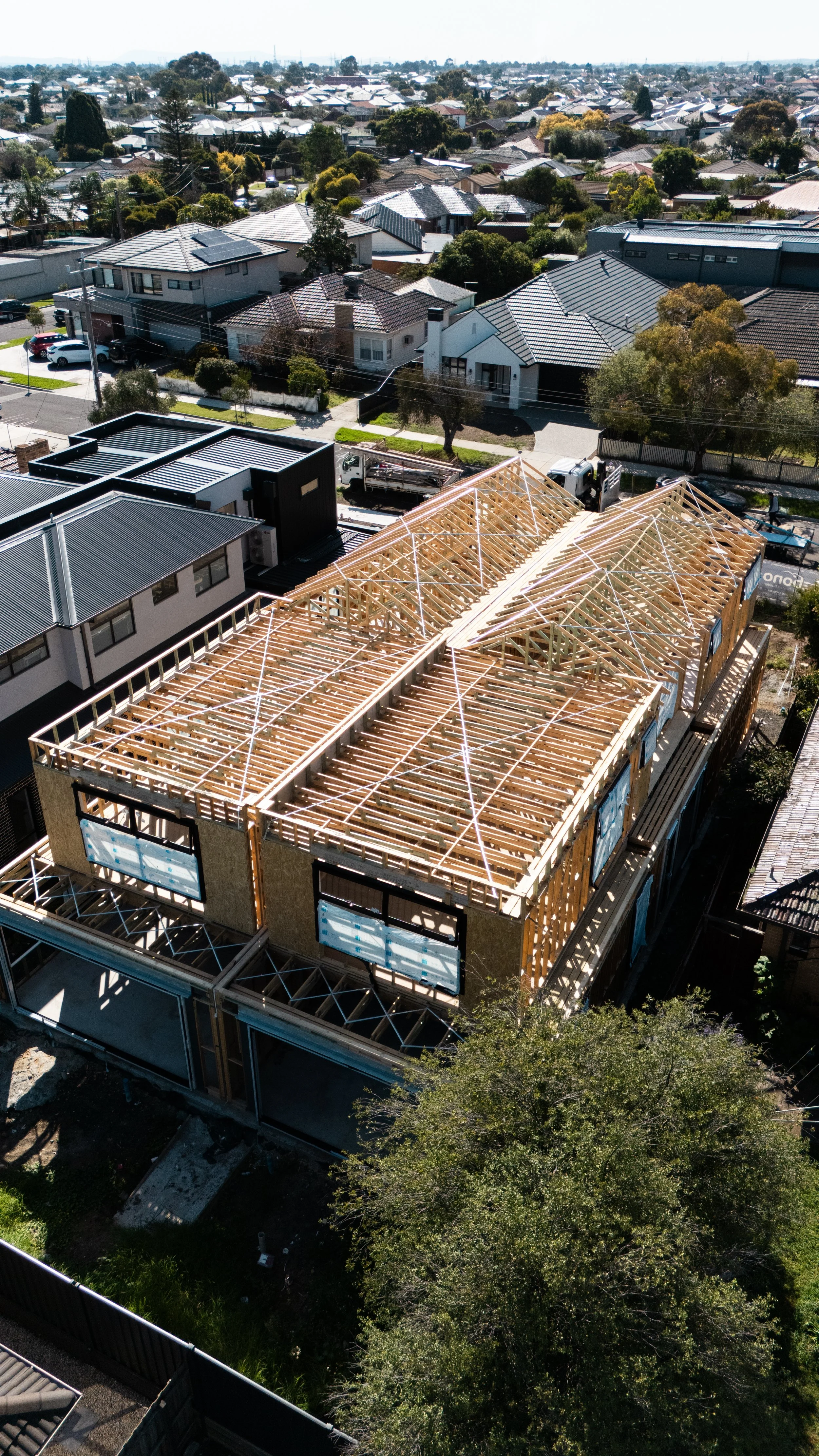 Aerial view of a house under construction, showing the wooden framework for the roof and upper floors