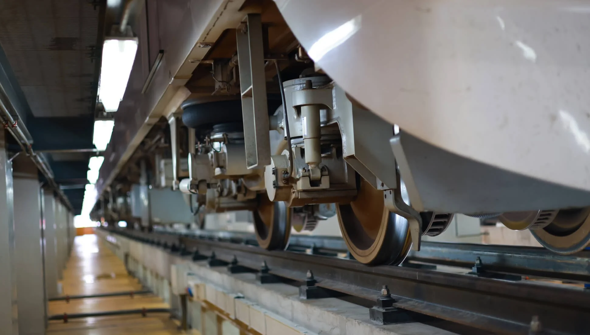 Close-up view of a model train on track, showing detailed mechanical components and wheels underneath the train car.