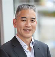 Professional headshot of a man in a suit smiling.