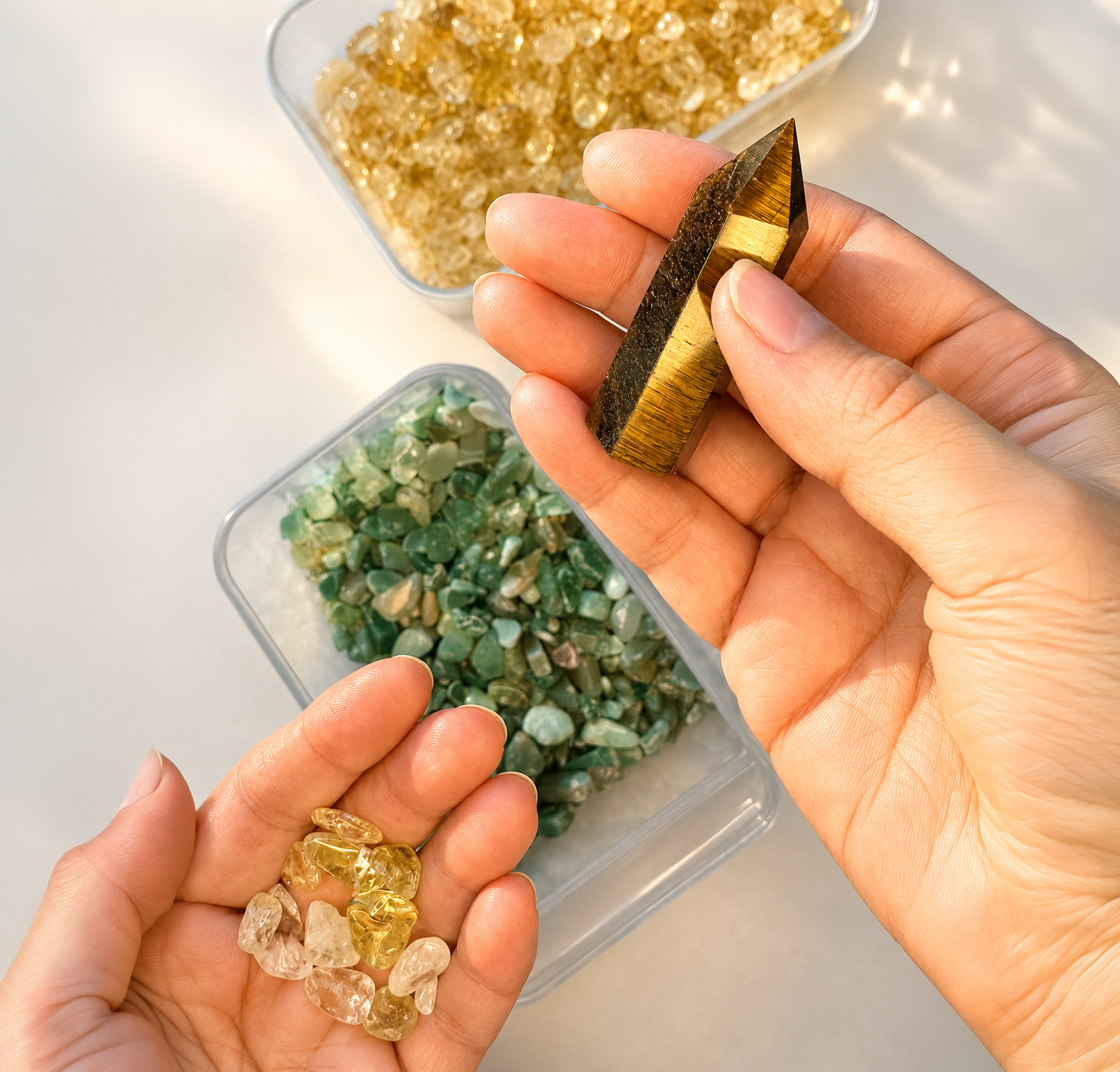 Person holding small polished amber stones, with two containers of similar stones in the background.