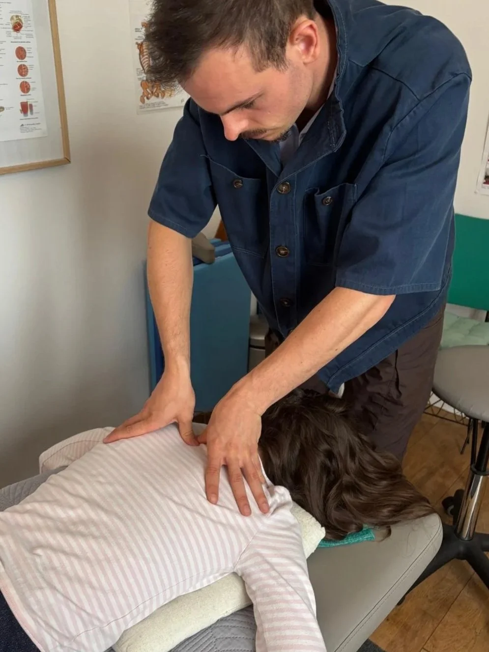 Un homme pratique la massothérapie sur une personne allongée sur une table. La personne reçoit un massage dans la région du dos.