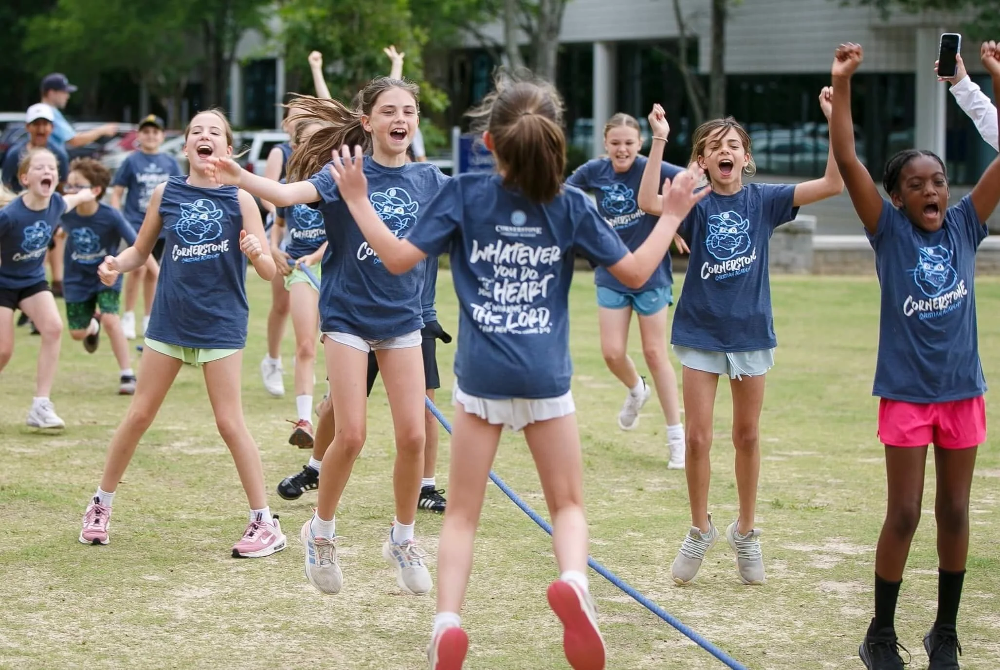 Students jumping to celebrate with Bible verse on shirts at Cornerstone Christian Academy