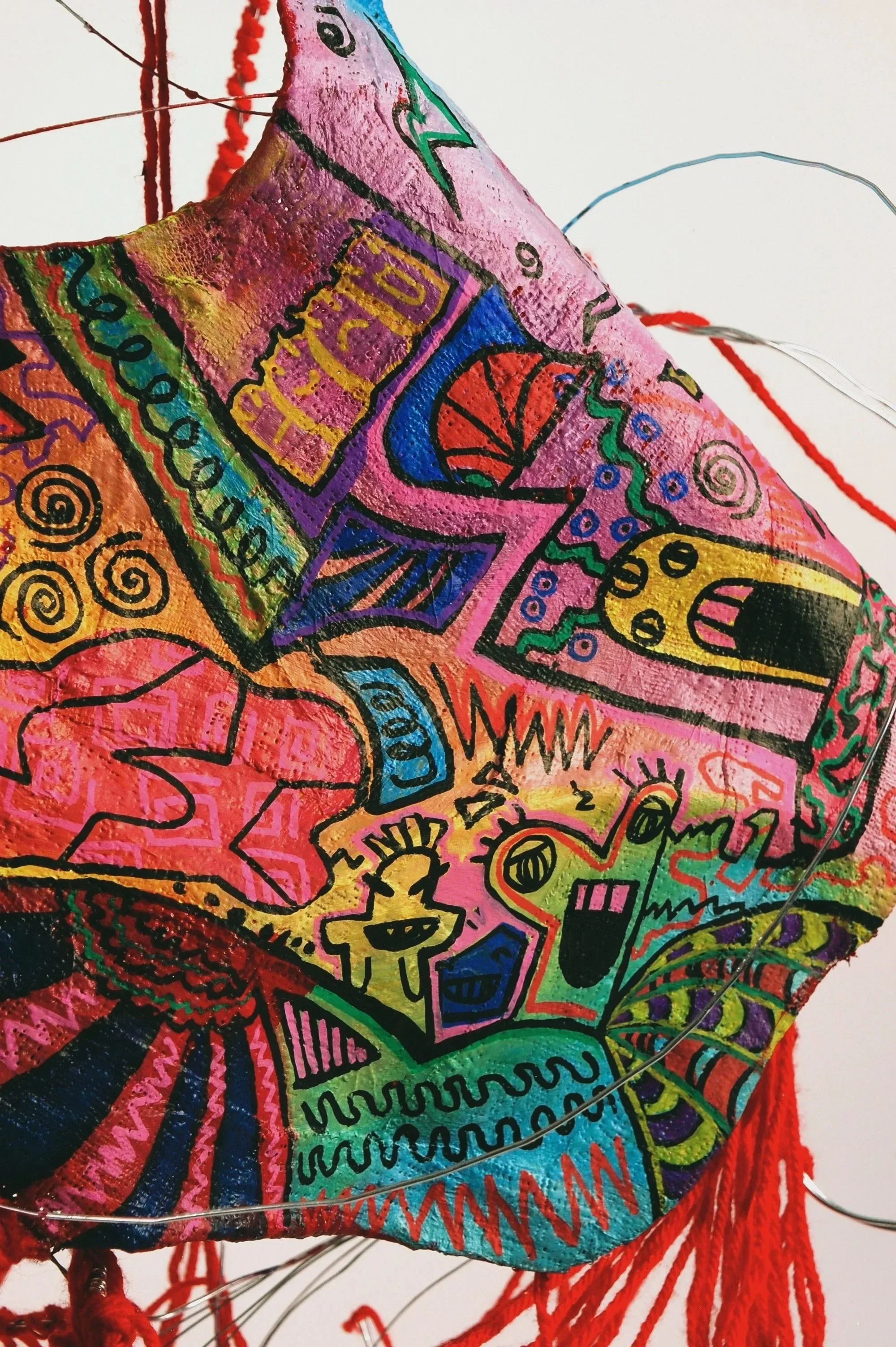 Colorful fabric with various abstract and cartoon-like doodles, including faces, shapes, and patterns.