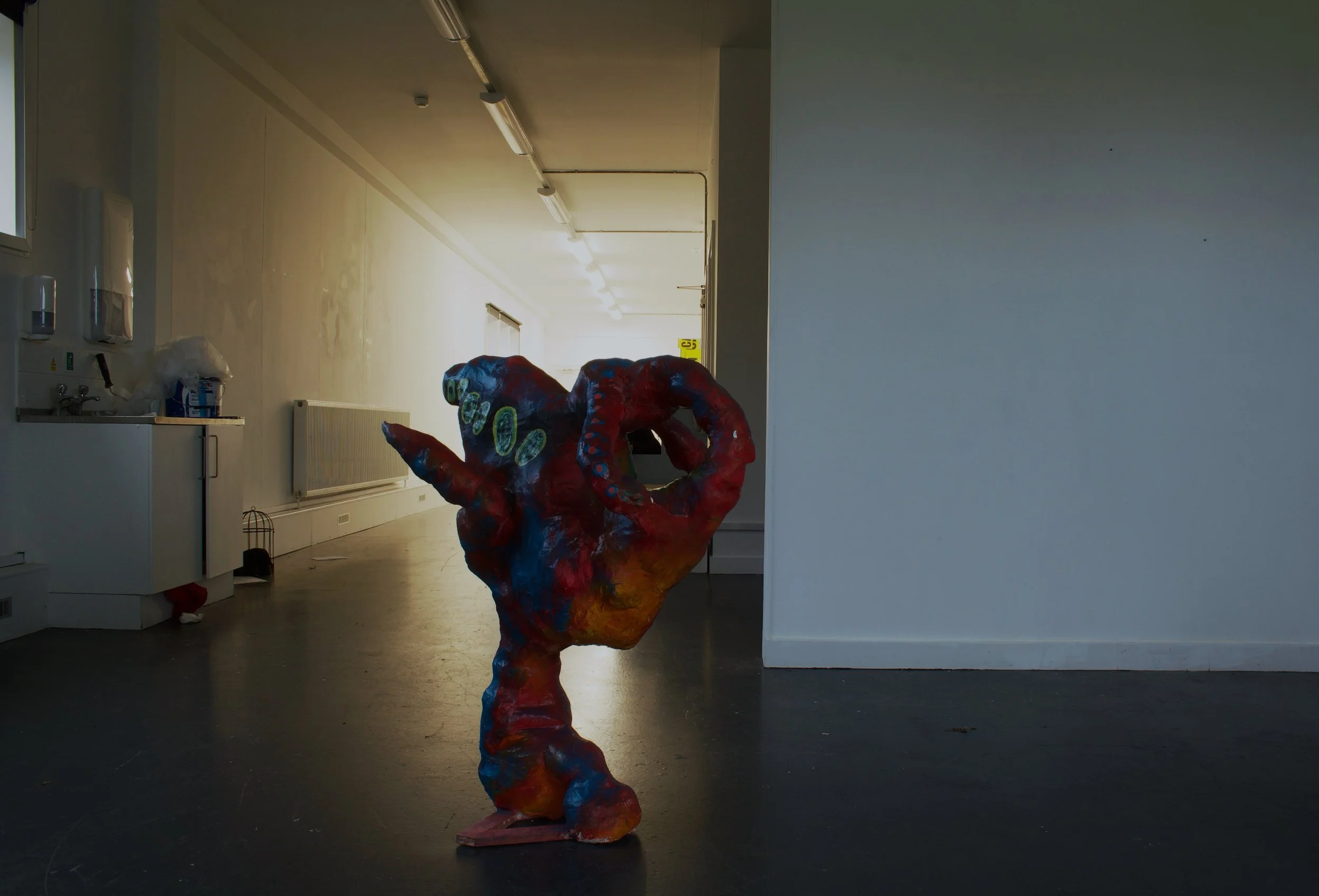 Colorful hand sculpture in an empty room with white walls and a black floor.