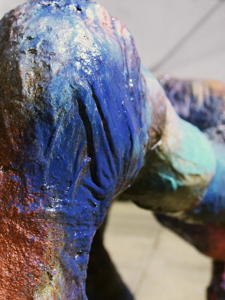 Close-up of a colorful, textured sculpture with blue and black streaks.