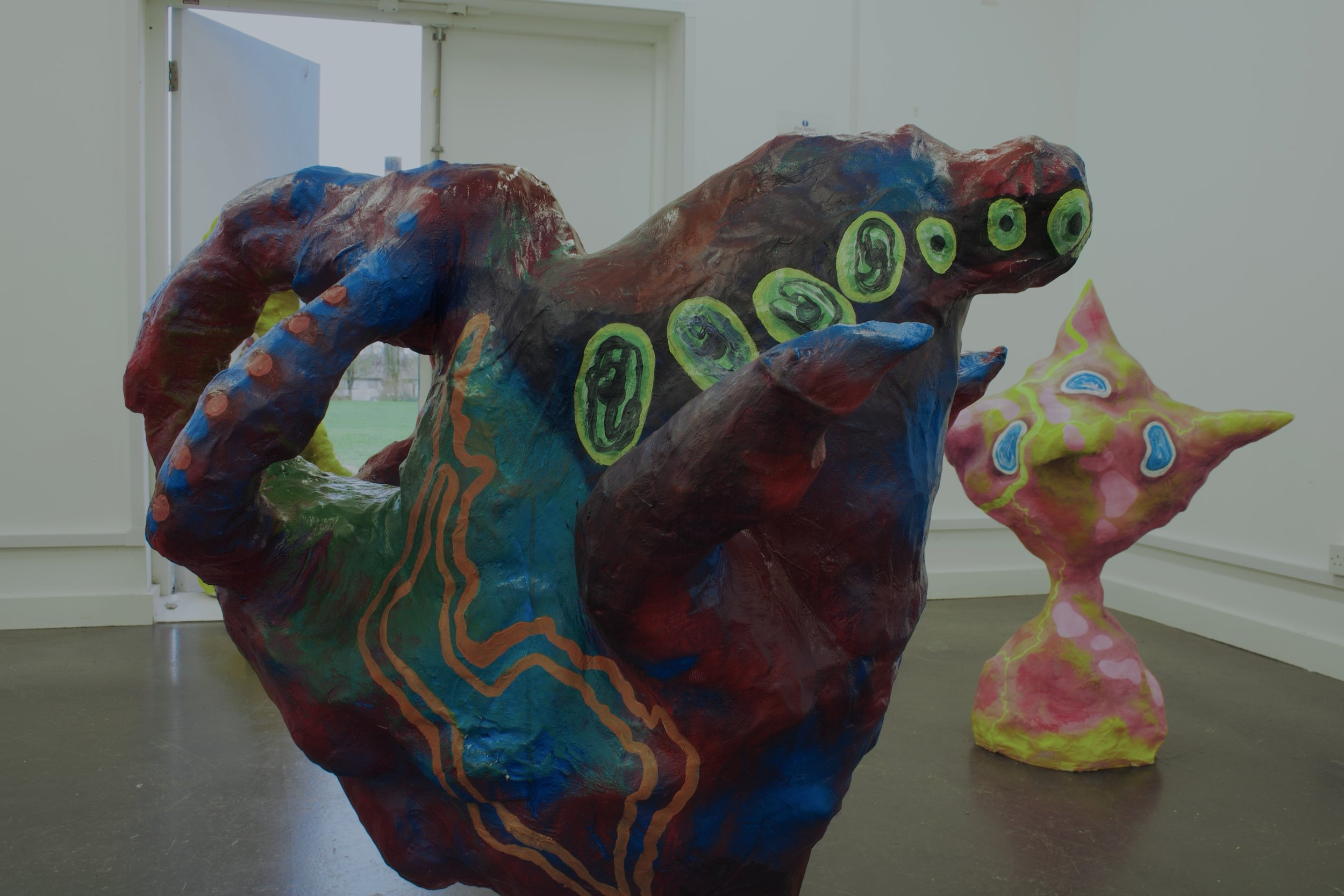 Colorful abstract sculptures with organic, creature-like shapes and bright patterns in an indoor gallery.